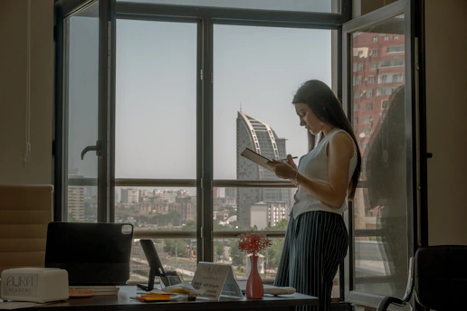 Woman reads by a window with a city view
