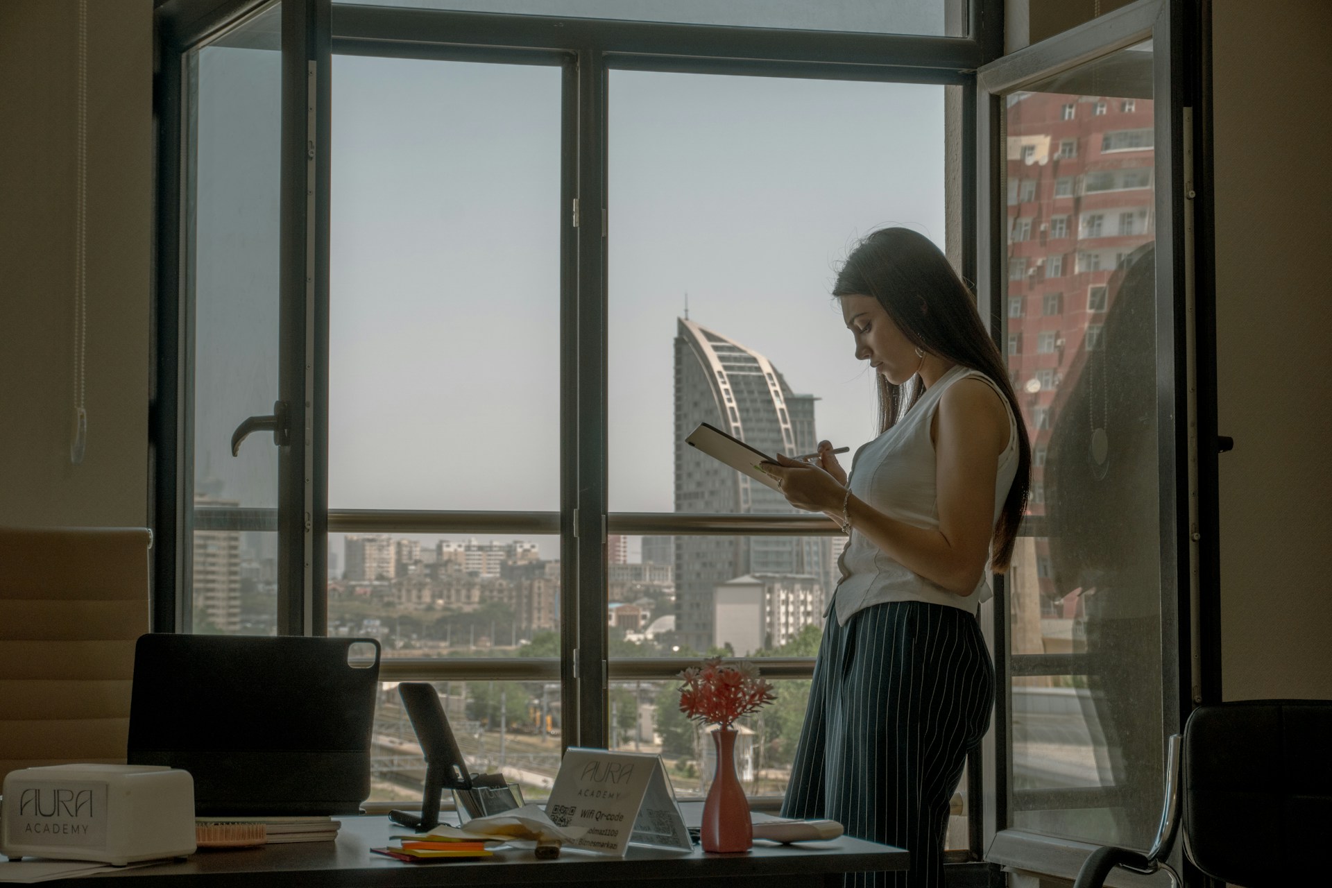 Woman reads by a window with a city view.