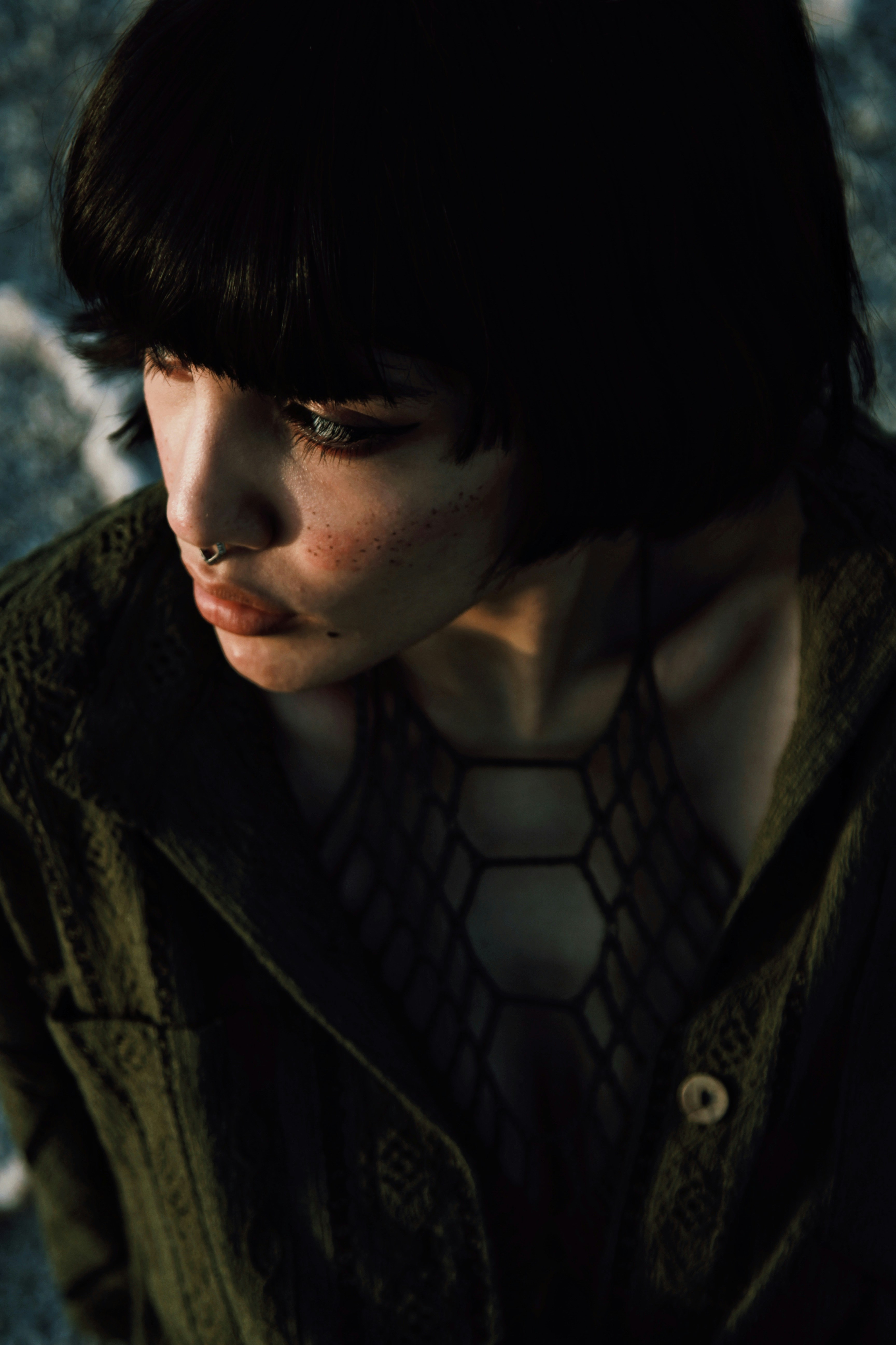 A person gazes downwards, with dark hair.