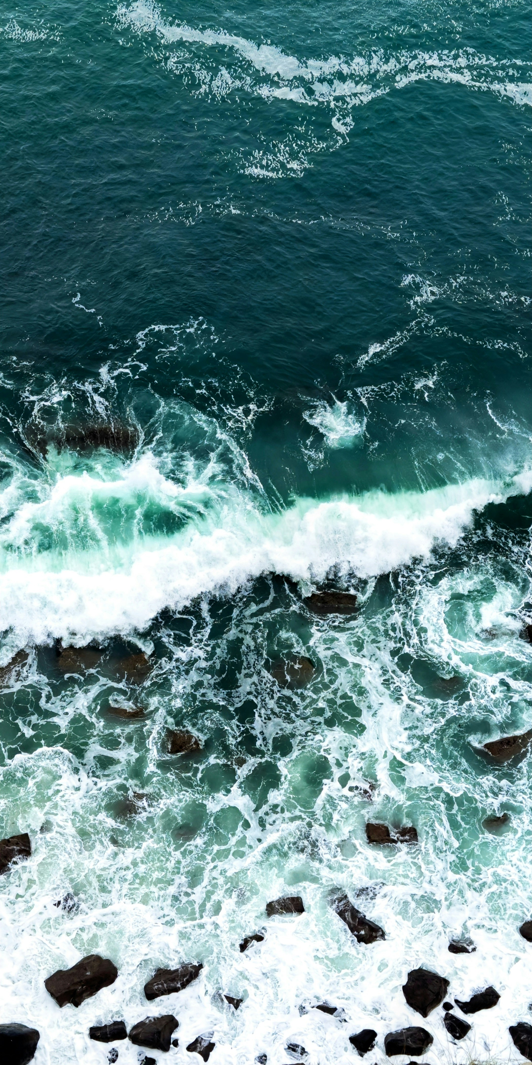 Ocean waves crash against the rocky shore.
