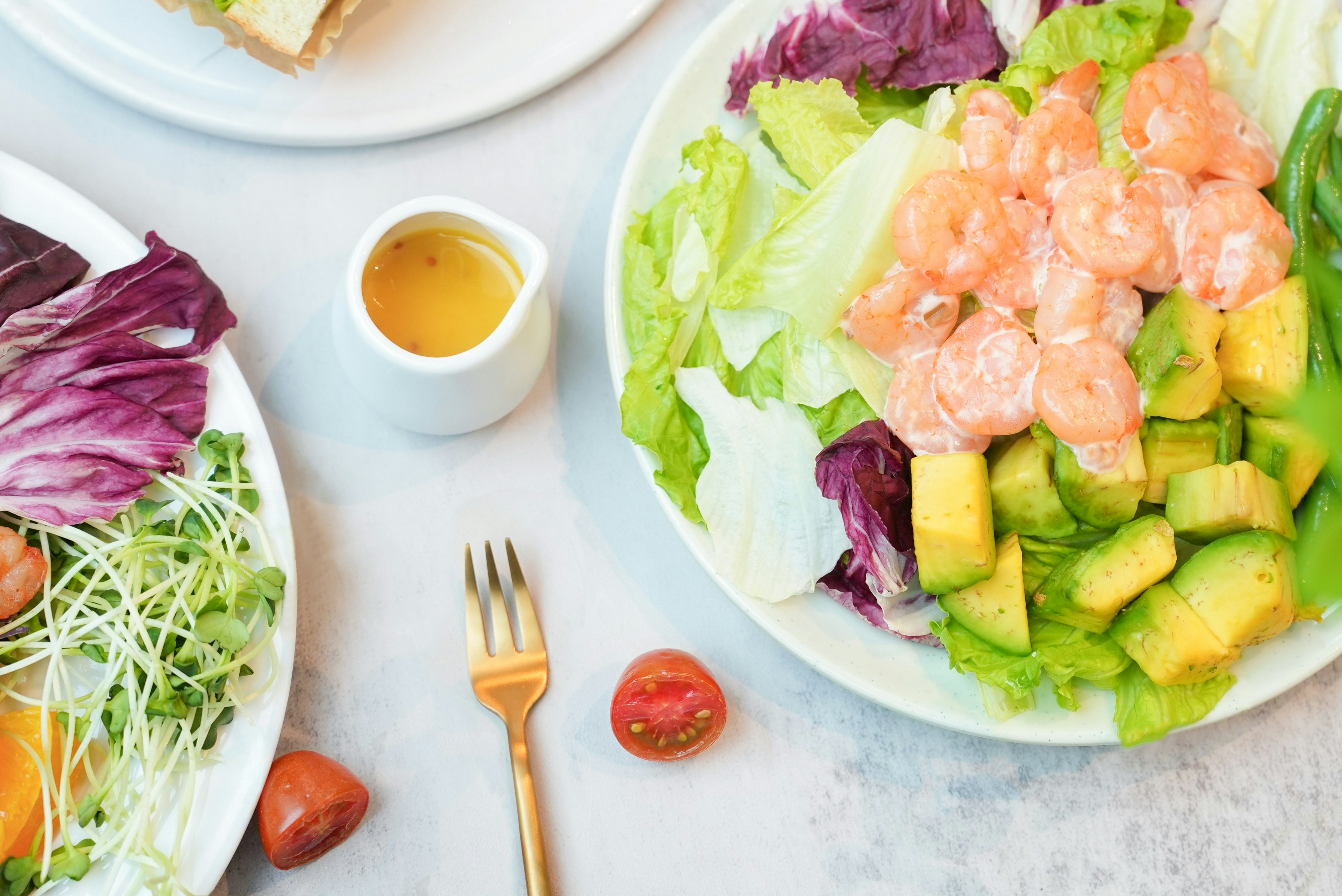 Salads with shrimp, avocado, and dressing displayed.