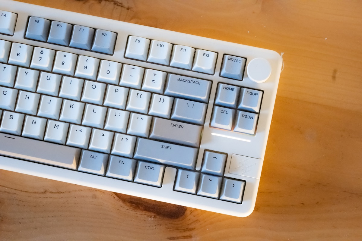 A white mechanical keyboard rests on a wooden surface.