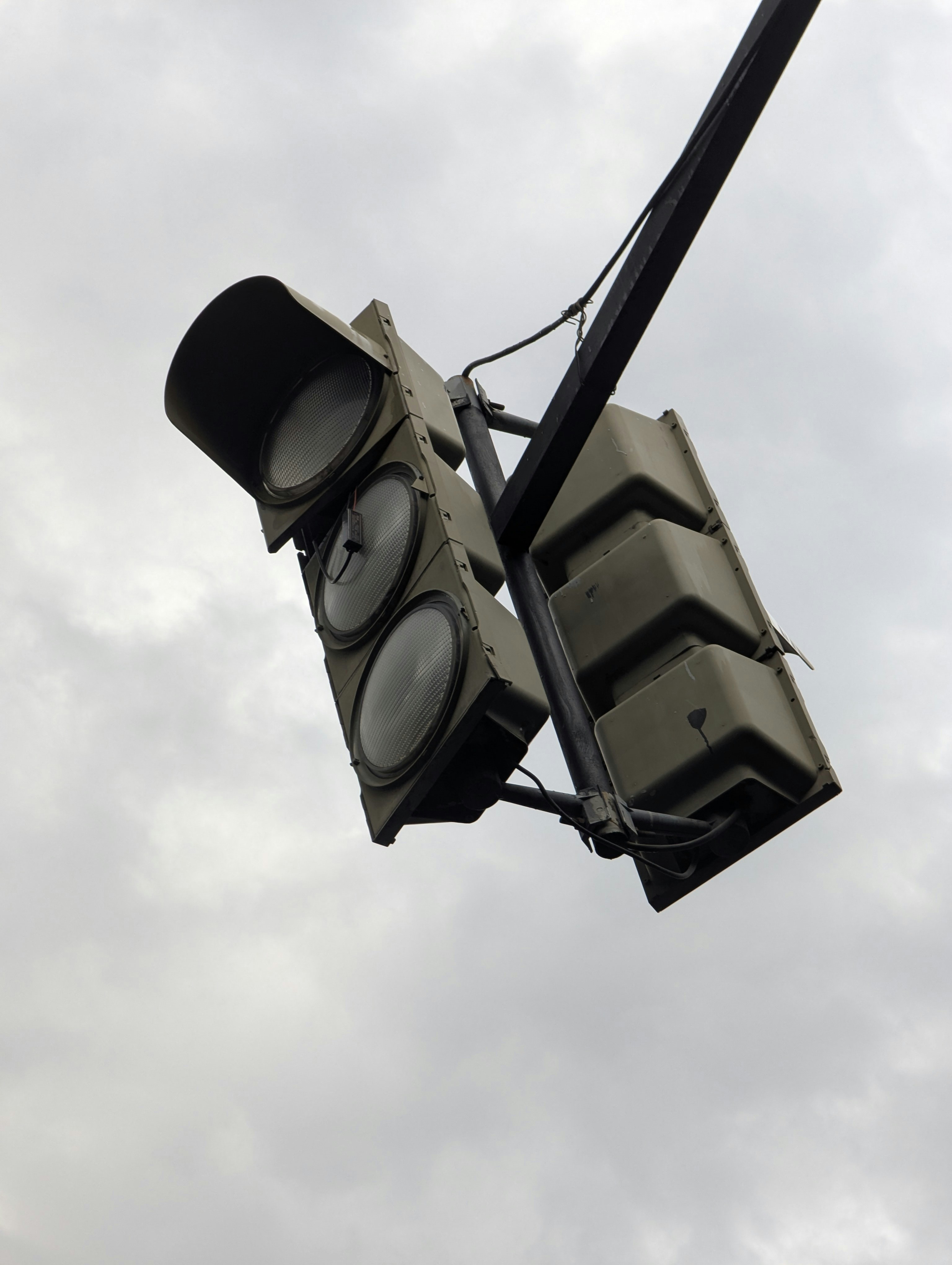 A traffic light hangs against a cloudy sky.