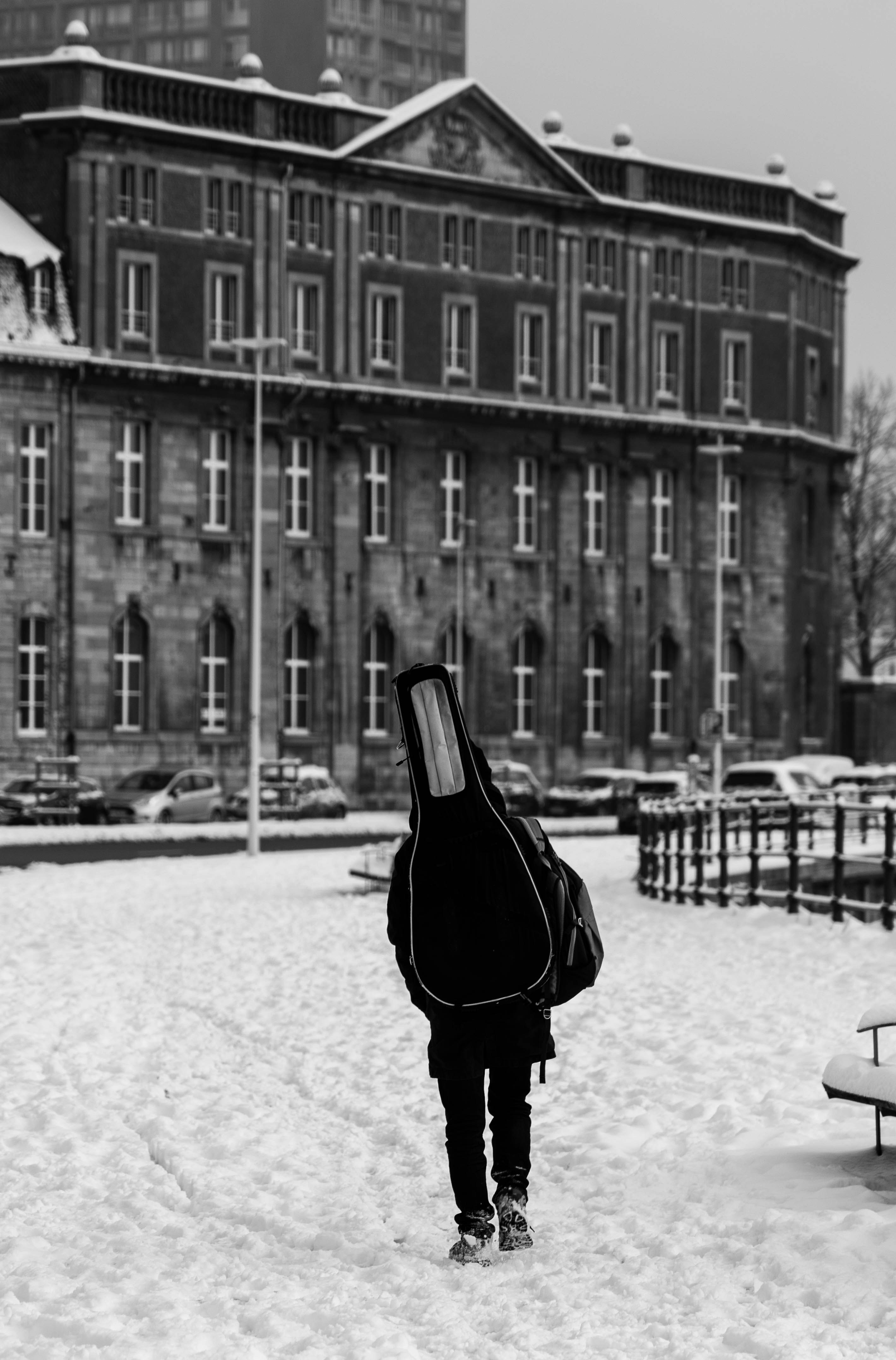 Eine Person läuft mit einer Gitarre im Schnee herum.