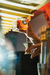 A bartender pours a drink into a jigger.