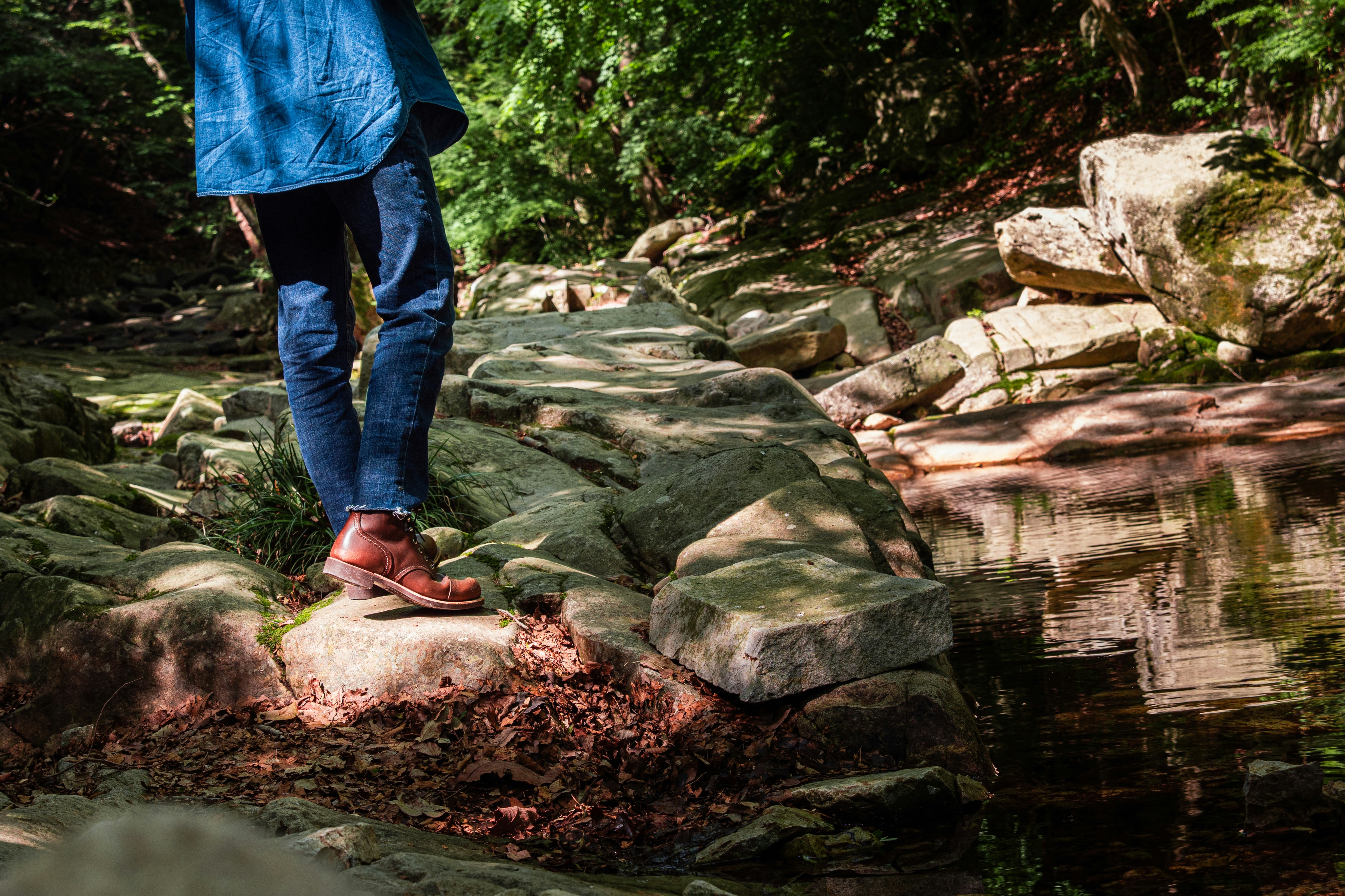 Person walks on a rocky path by a stream.