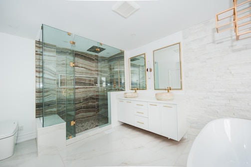 Modern, luxurious bathroom with glass shower and white finishes.