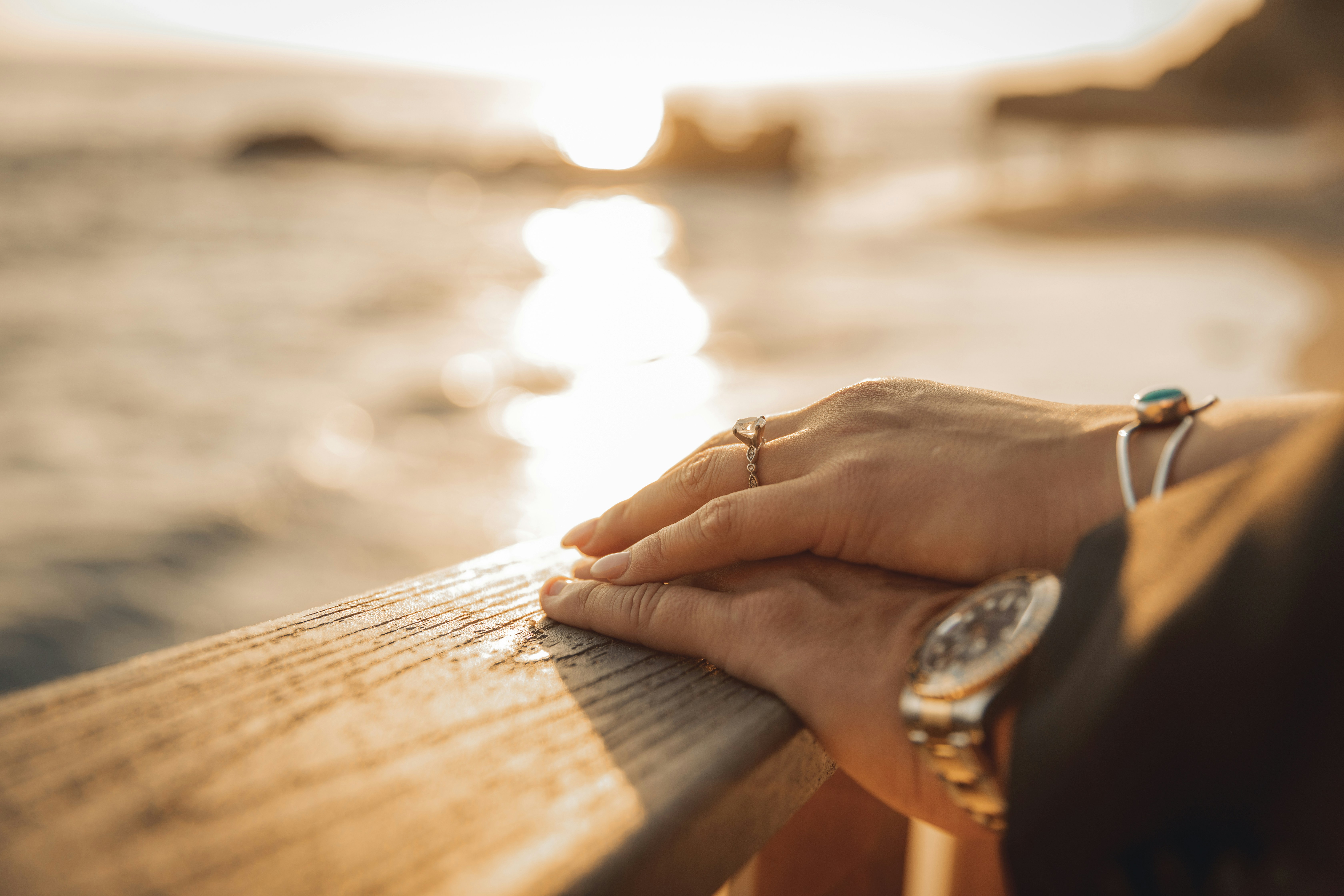 Hands resting on railing with the sunset in the background.