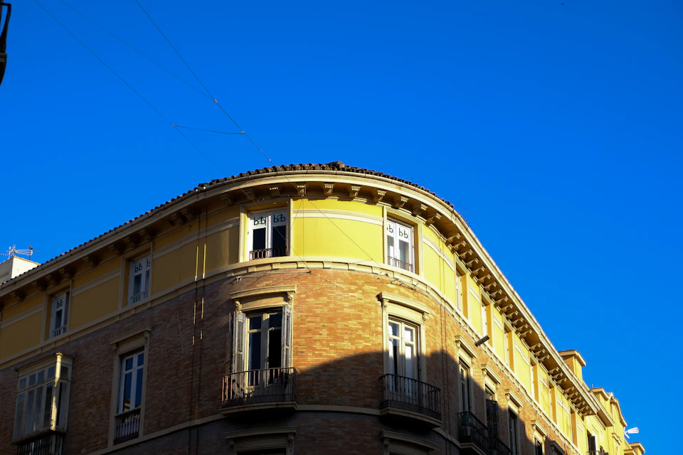 Corner building with yellow facade and white trim under clear blue sky