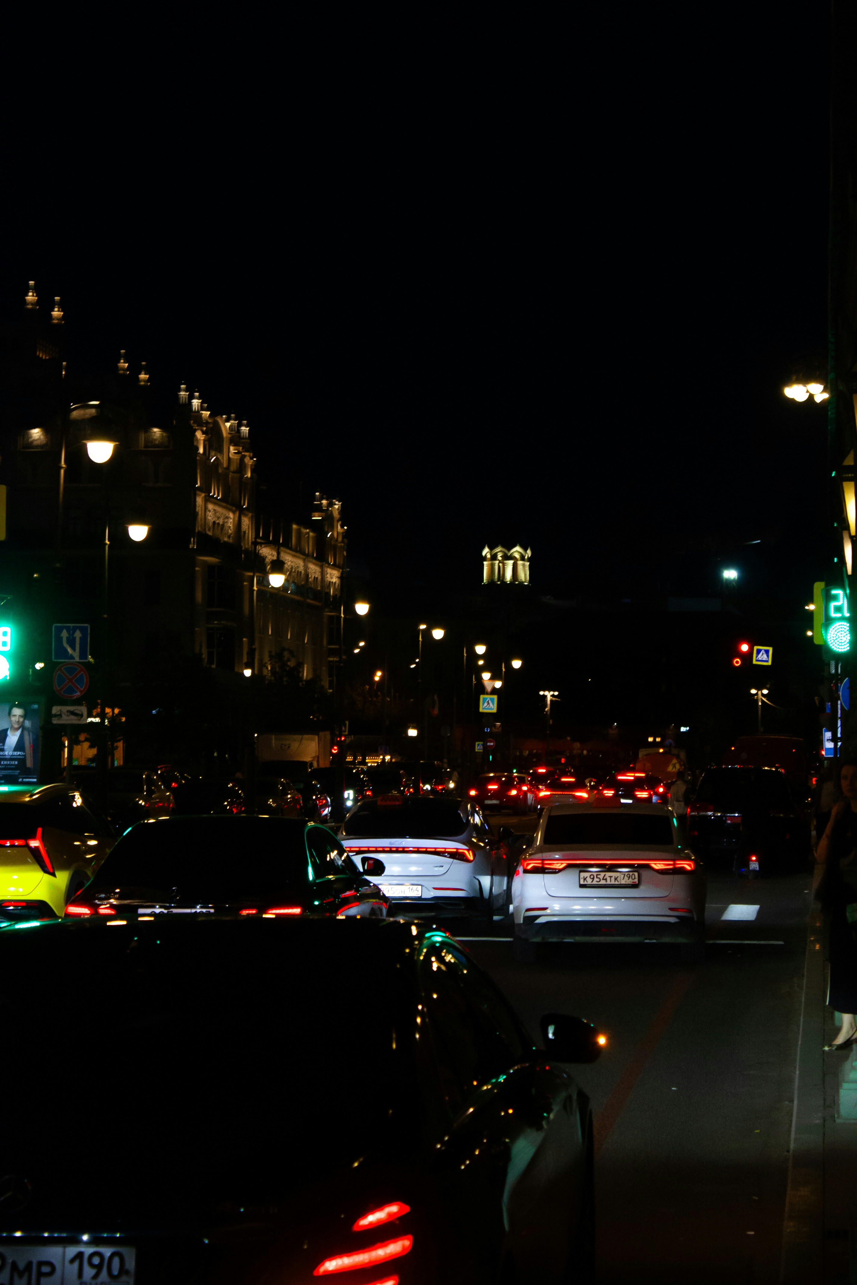Cars are stuck in traffic on a city street at night.