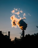 Smoke billows from a chimney at sunset.