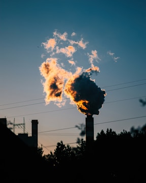 Smoke billows from a chimney at sunset.