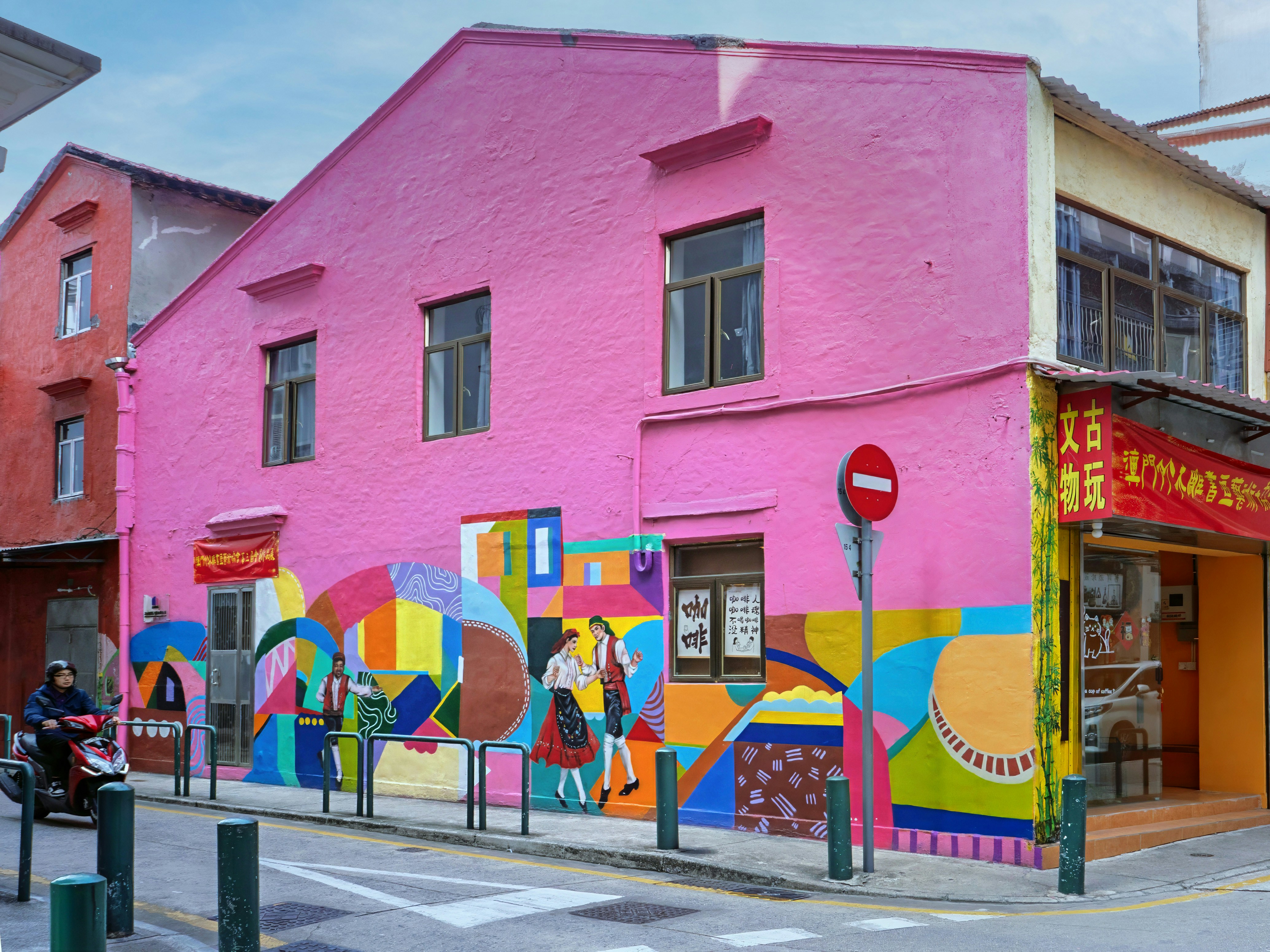 A bright pink building features colorful murals.