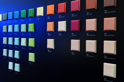 A wall displays square paint samples of many colors.