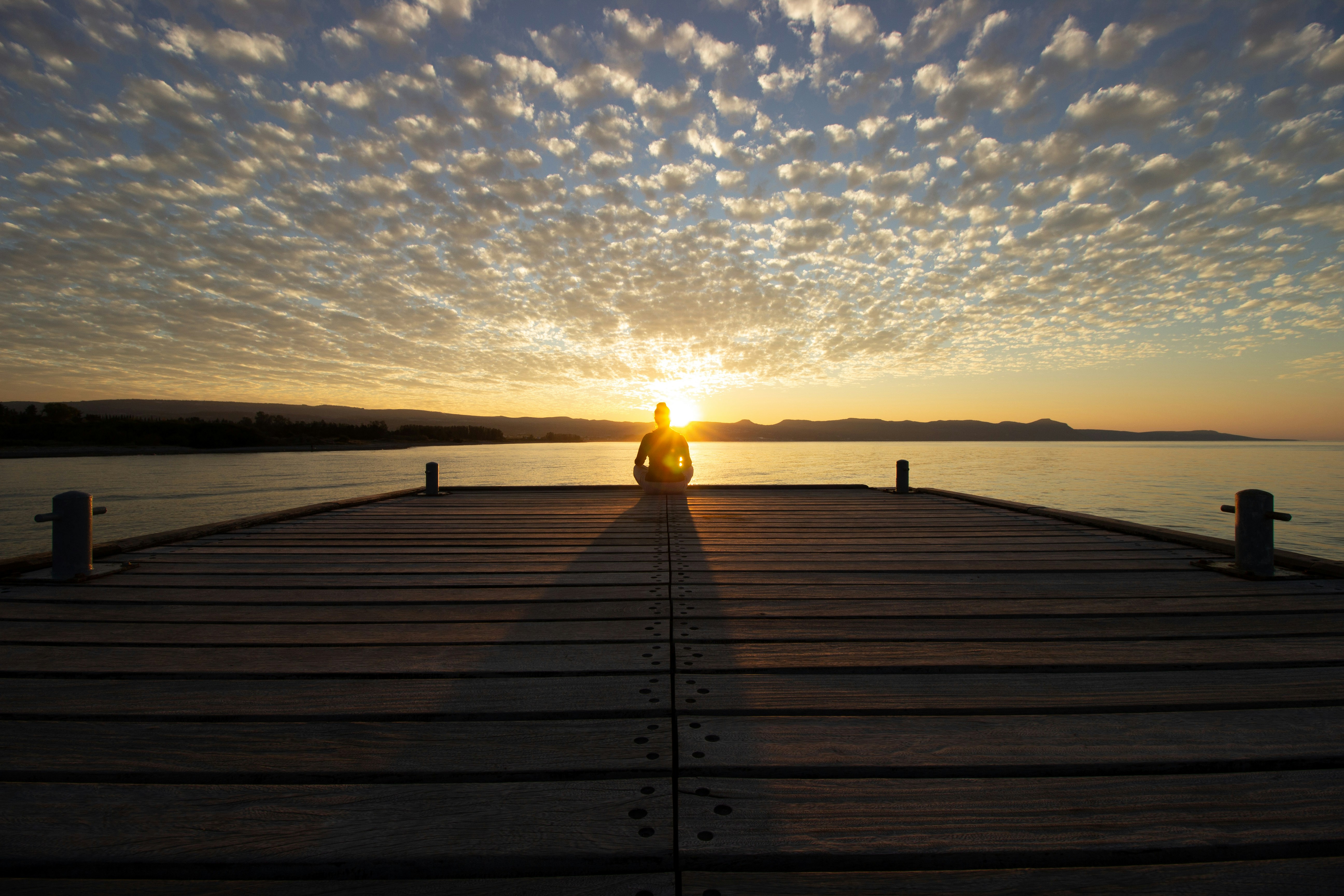 Meditating at sunrise on a pier.