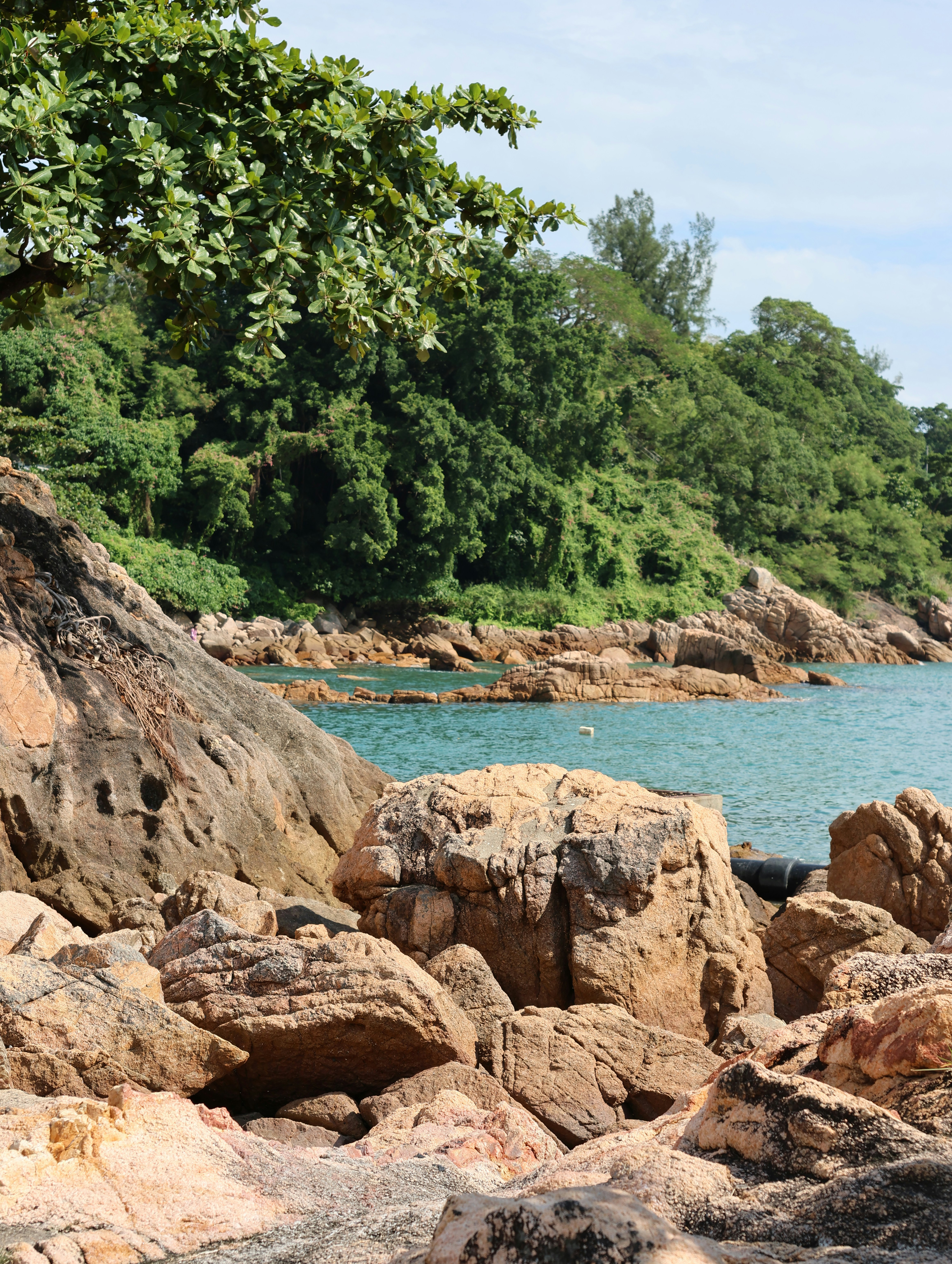 Eine felsige Küste trifft auf einen klaren blauen Ozean.