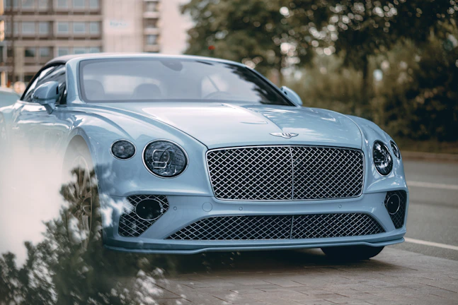 A blue bentley is parked on the side of the road.