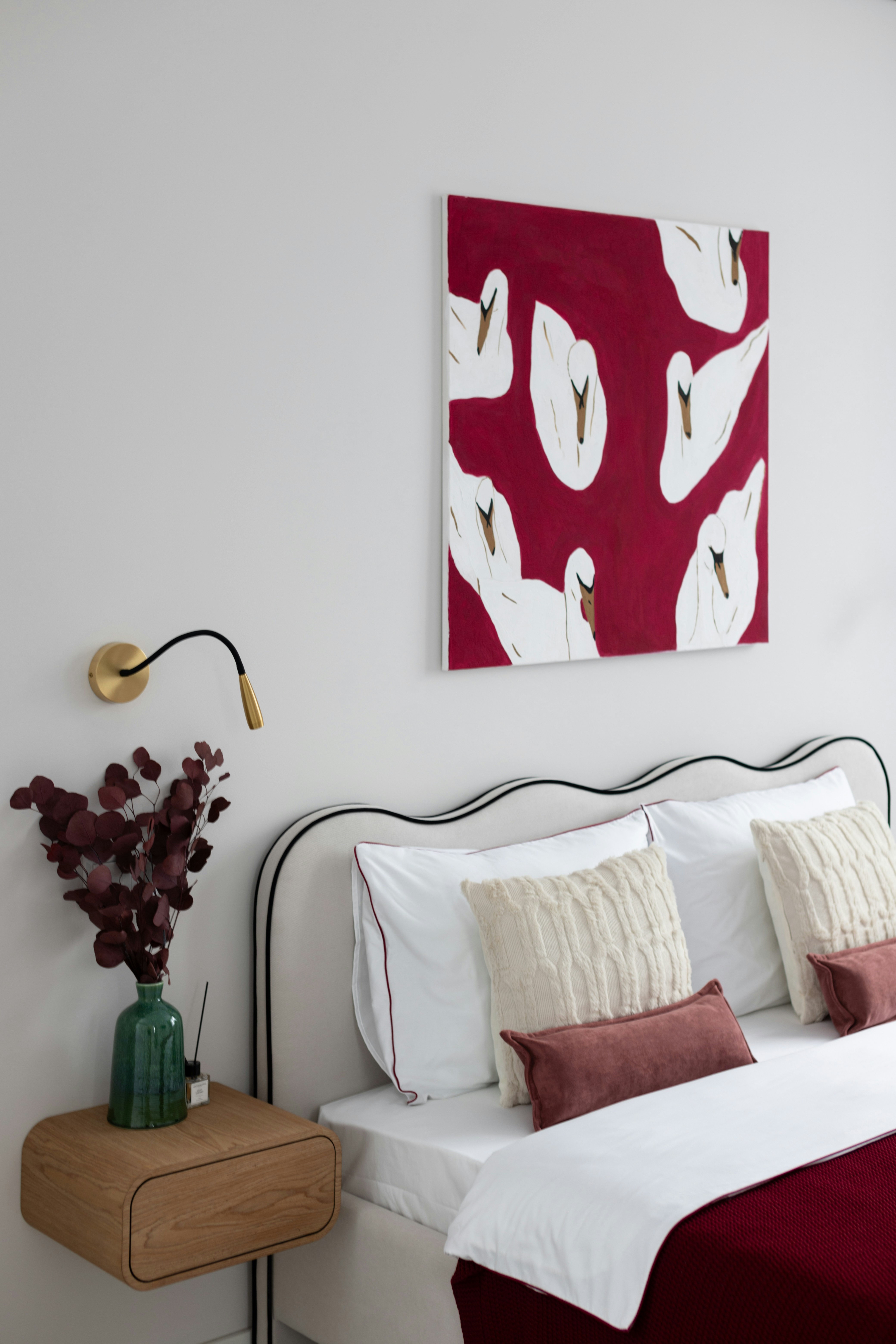 A bedroom features art, a bed, and a nightstand.