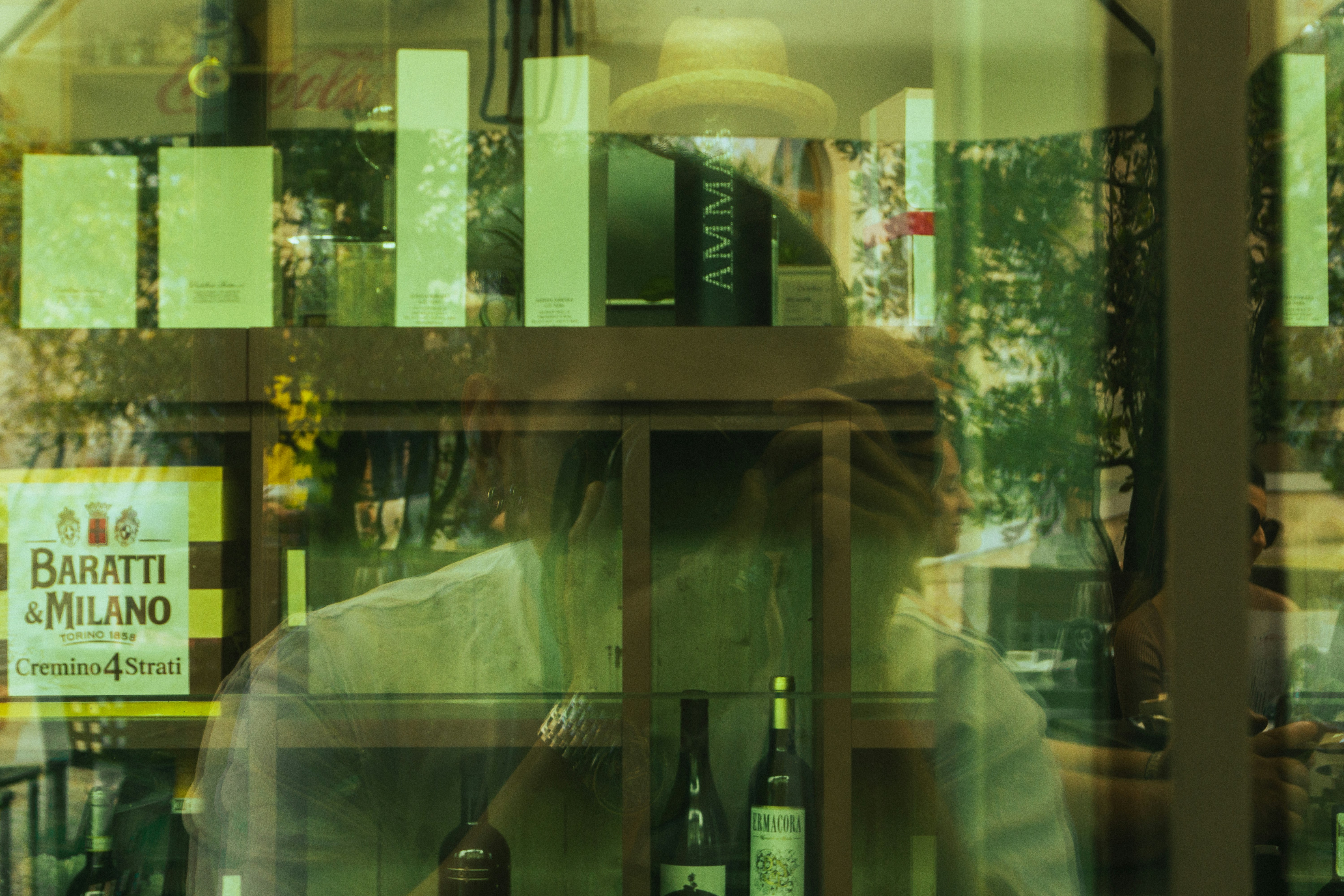 A man in a hat is reflected in a window.