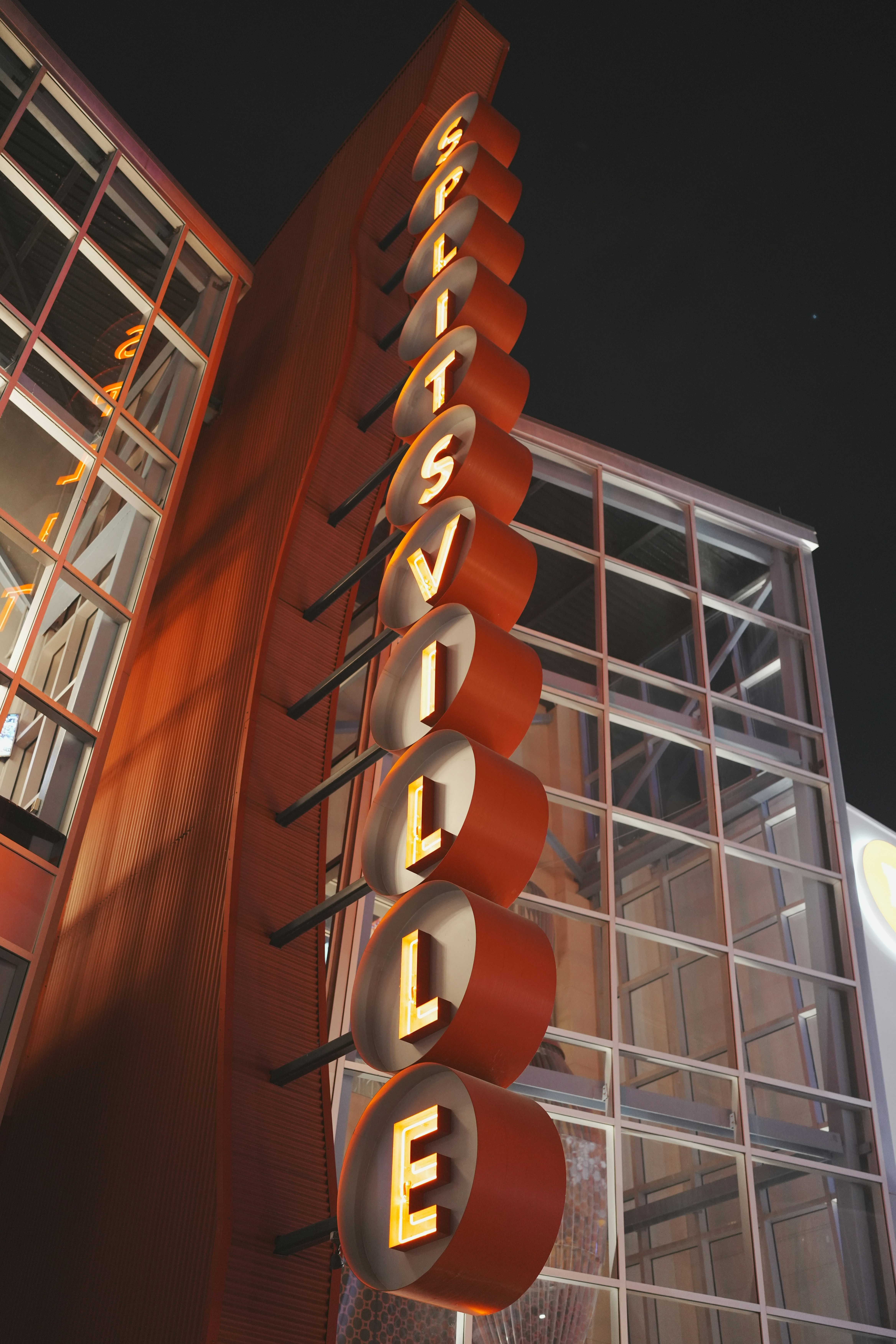 A brightly lit splitsville sign glows at night.