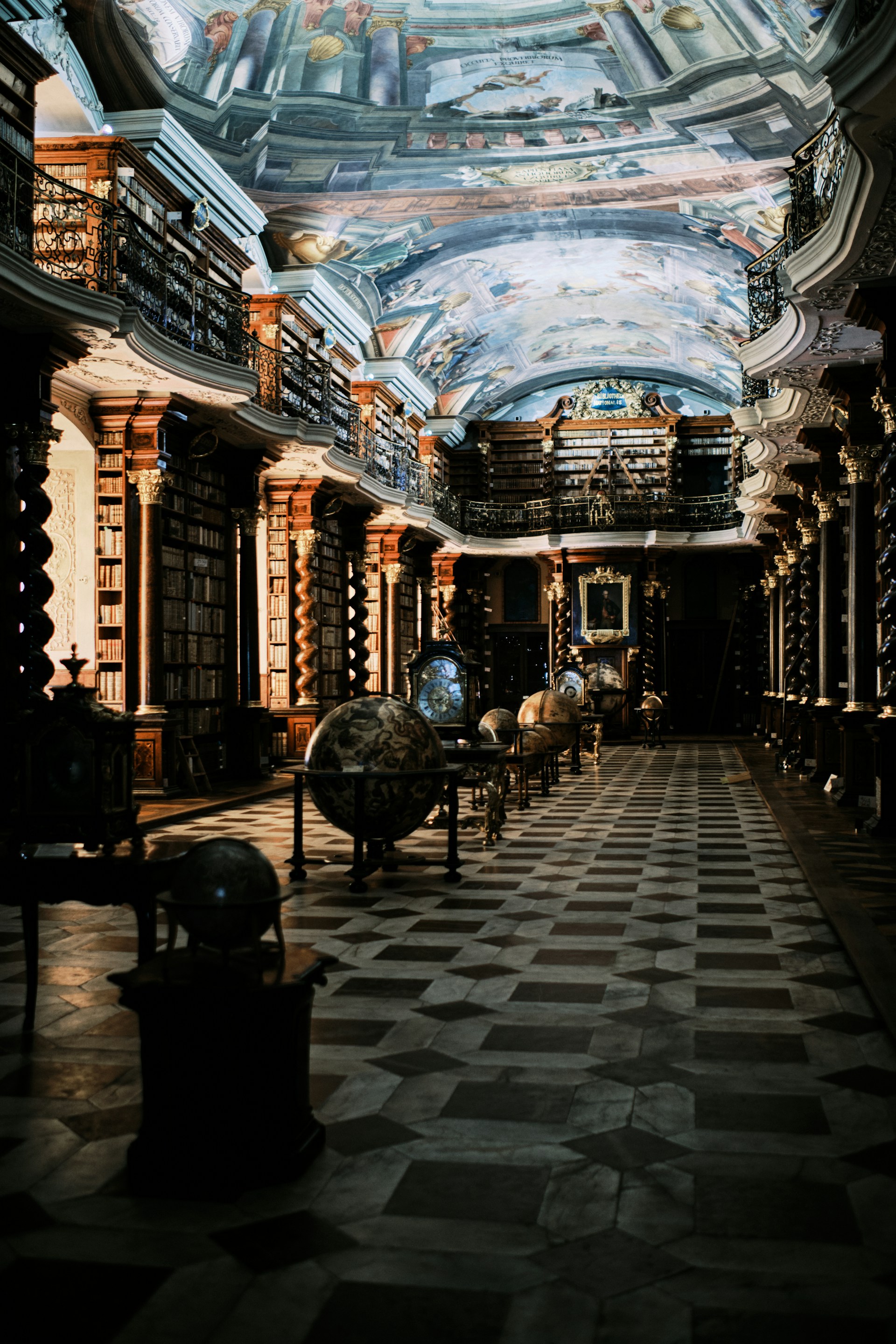 Grand library with bookshelves, globes, and a painted ceiling.
