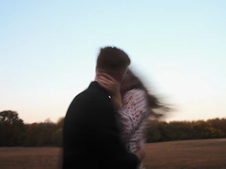 A blurry couple embraces and kisses outdoors.