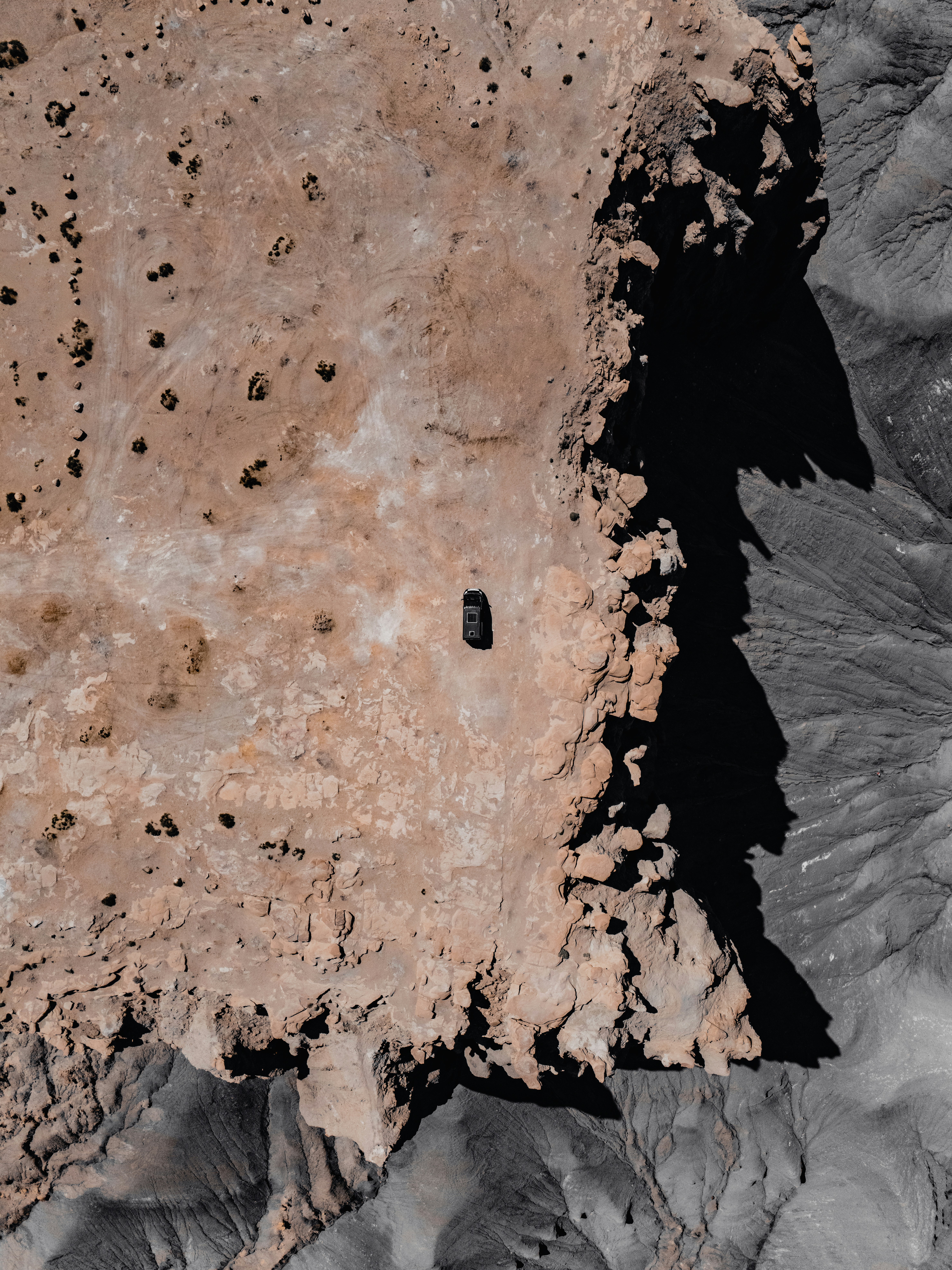 An aerial view of a car on barren land
