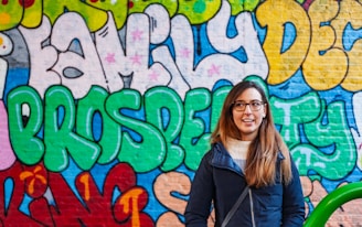 Woman smiles in front of colorful graffiti art.