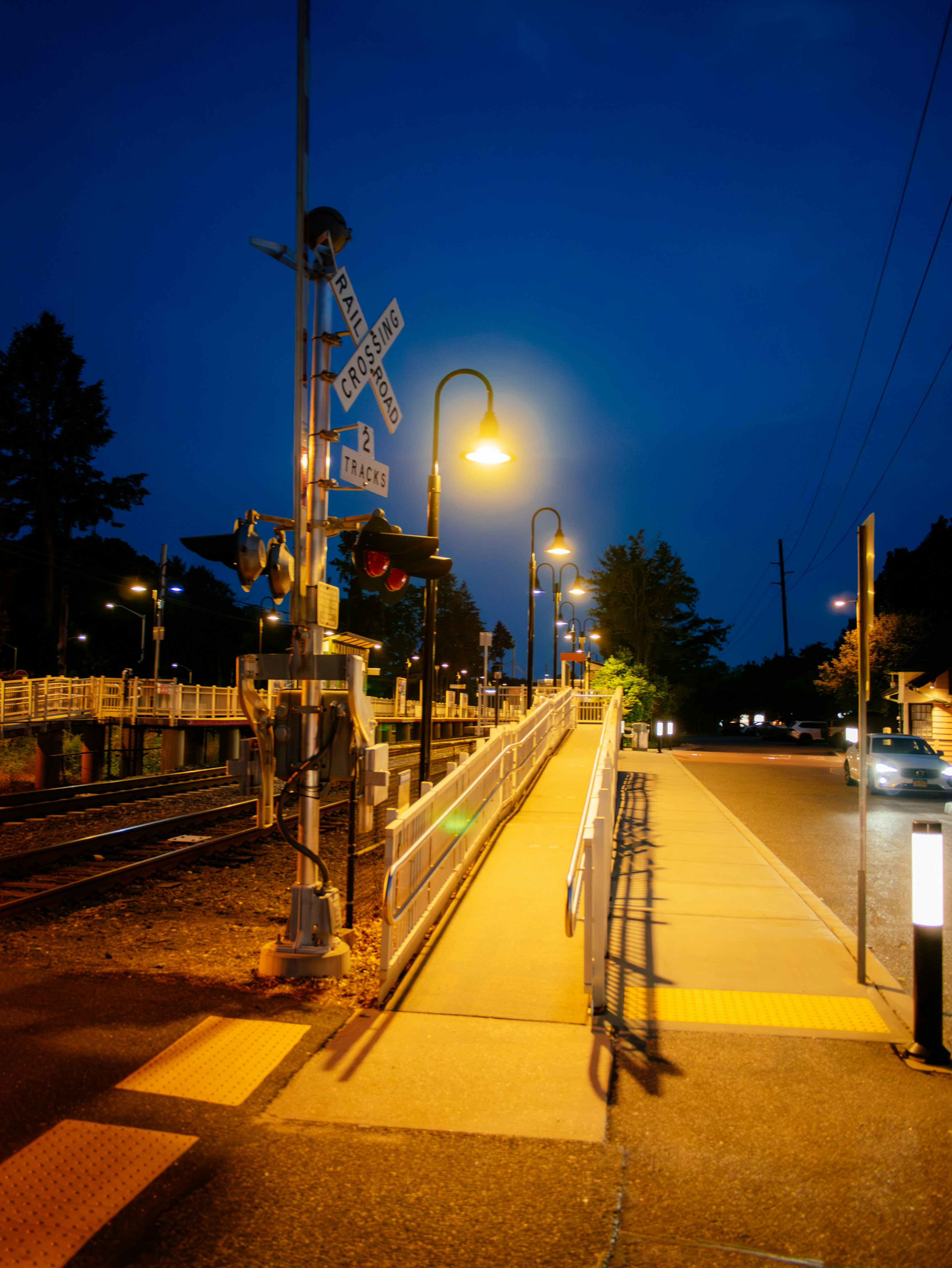 Nighttime view of a train crossing with street lights.