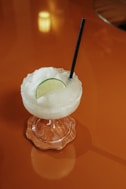 A margarita with a lime wedge on a red surface.