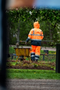 A worker in orange gear tends to the garden.