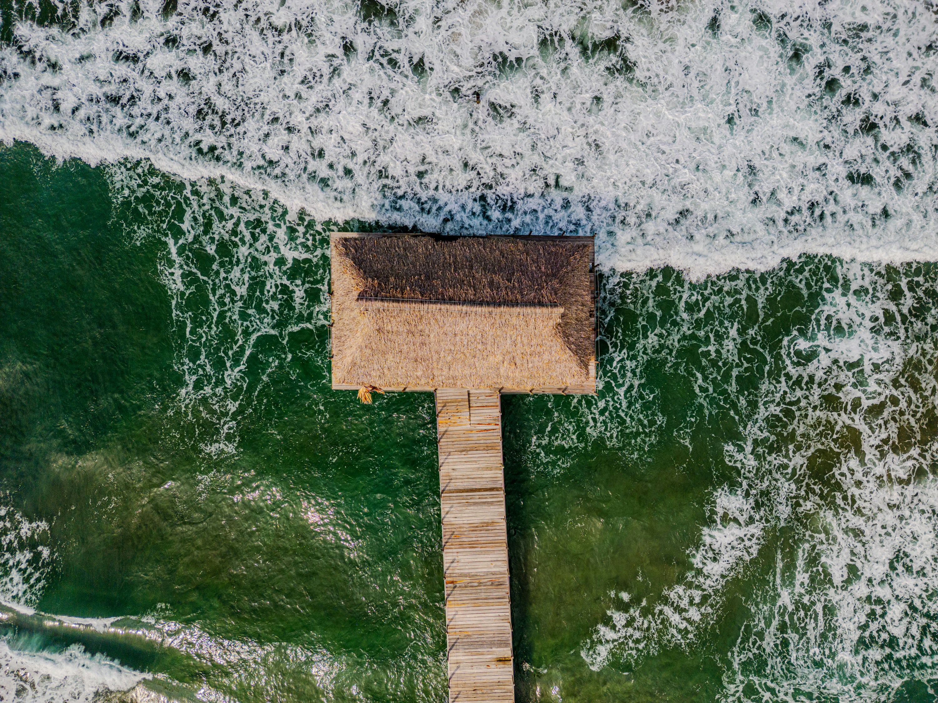 Pier with a building on a wavy ocean.