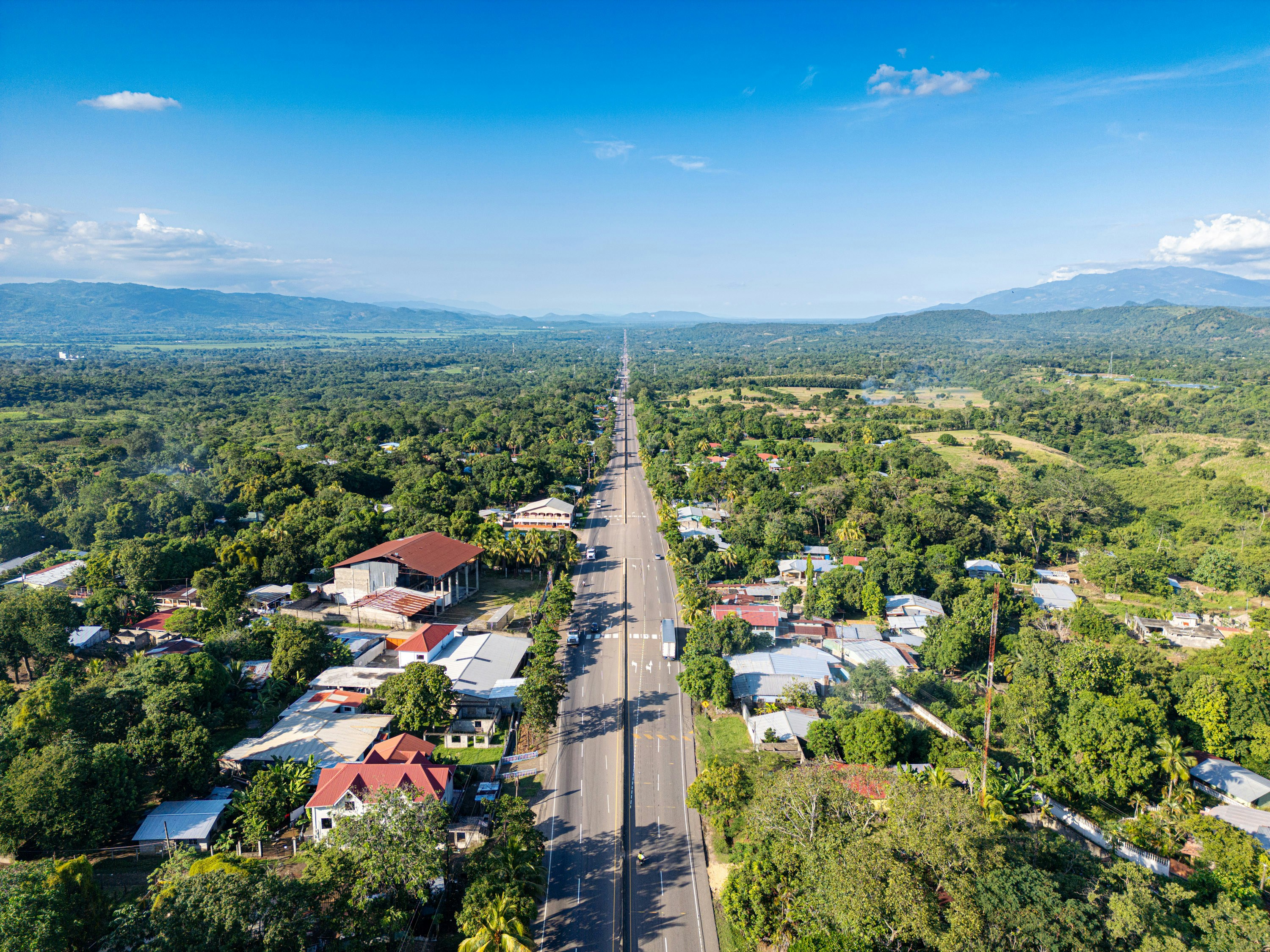 A long road leads through a verdant town.