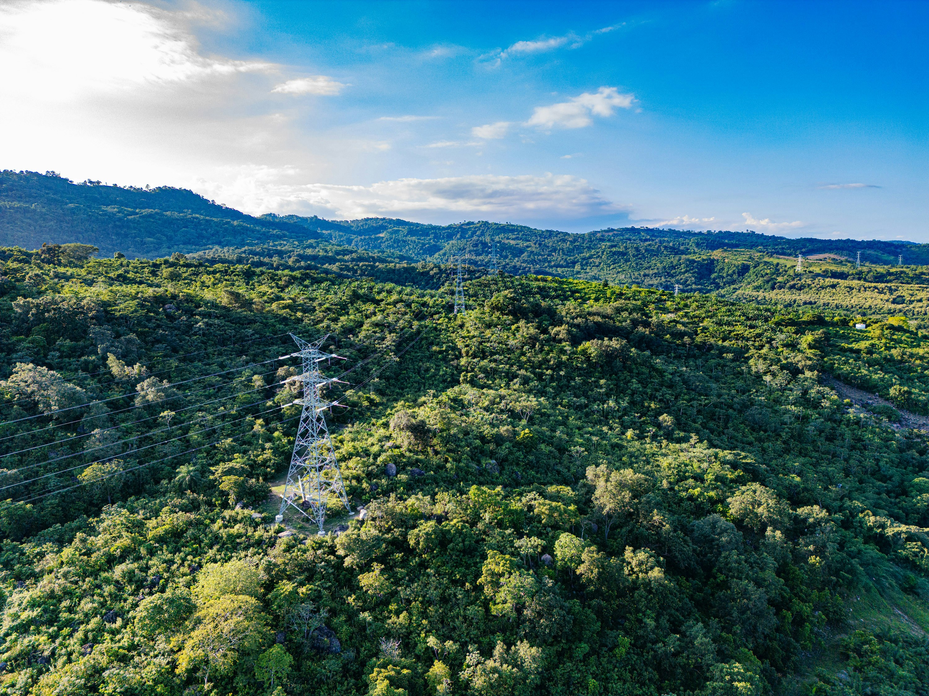 Power lines snake through a verdant, mountainous landscape.