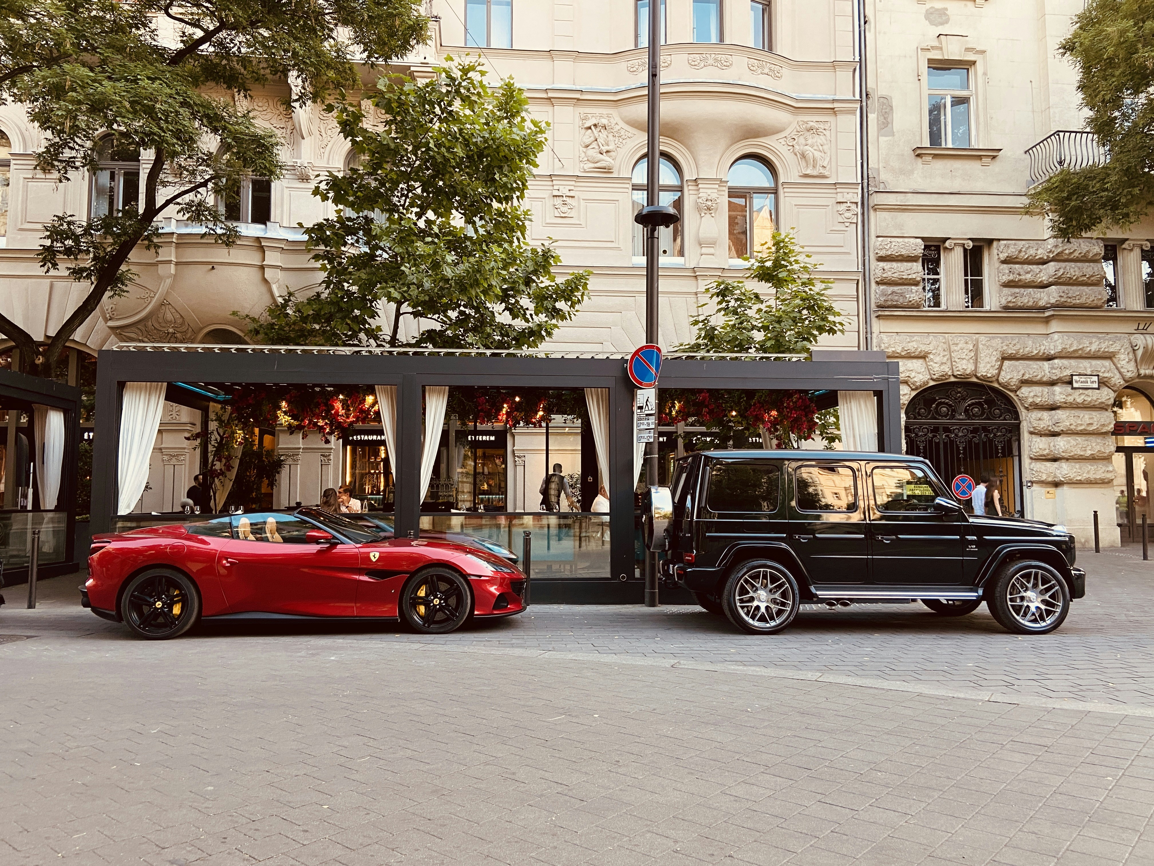 Luxury cars parked outside a cafe.