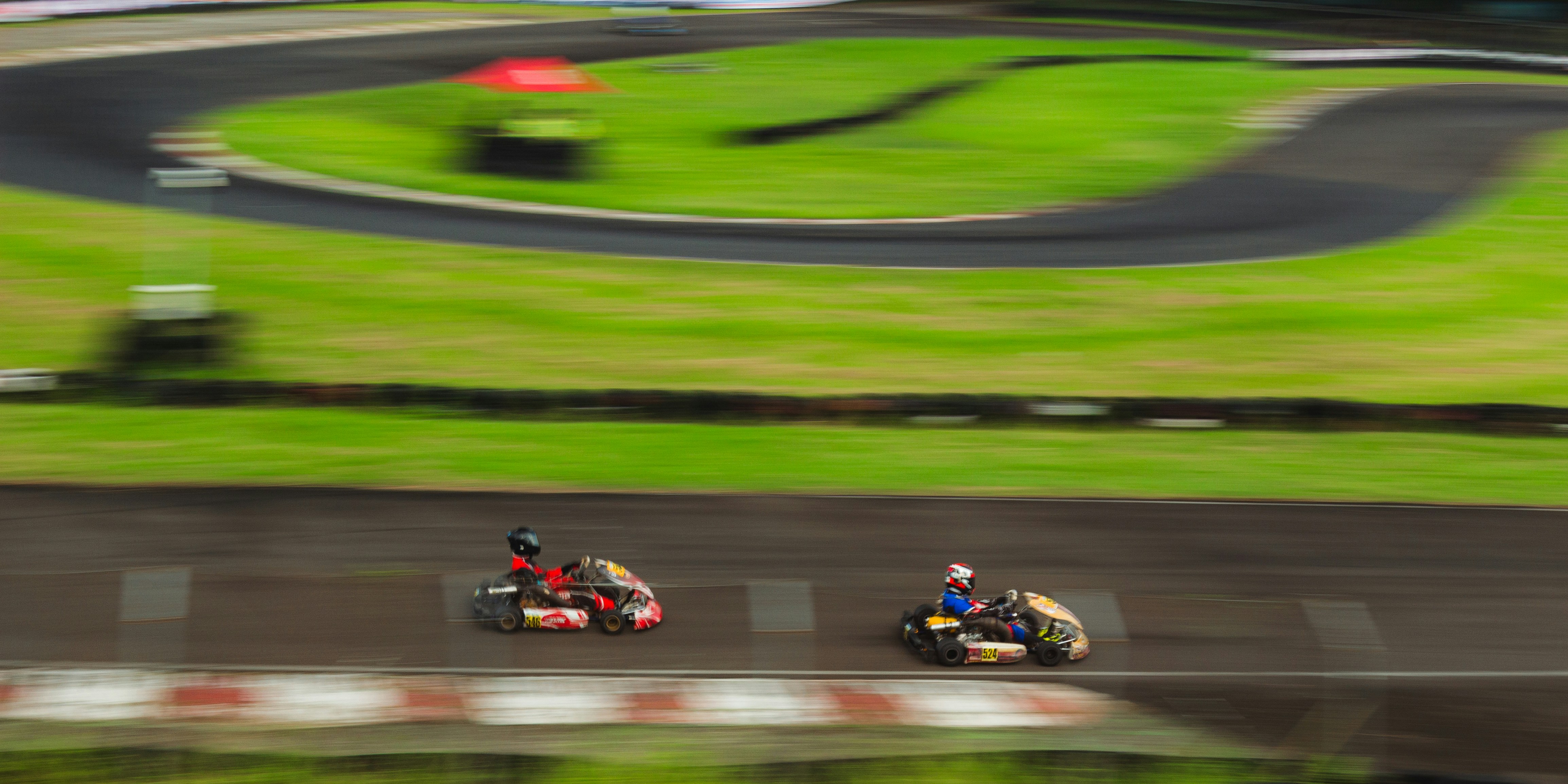 Competitive racing go karts racing at high speed around a circuit track