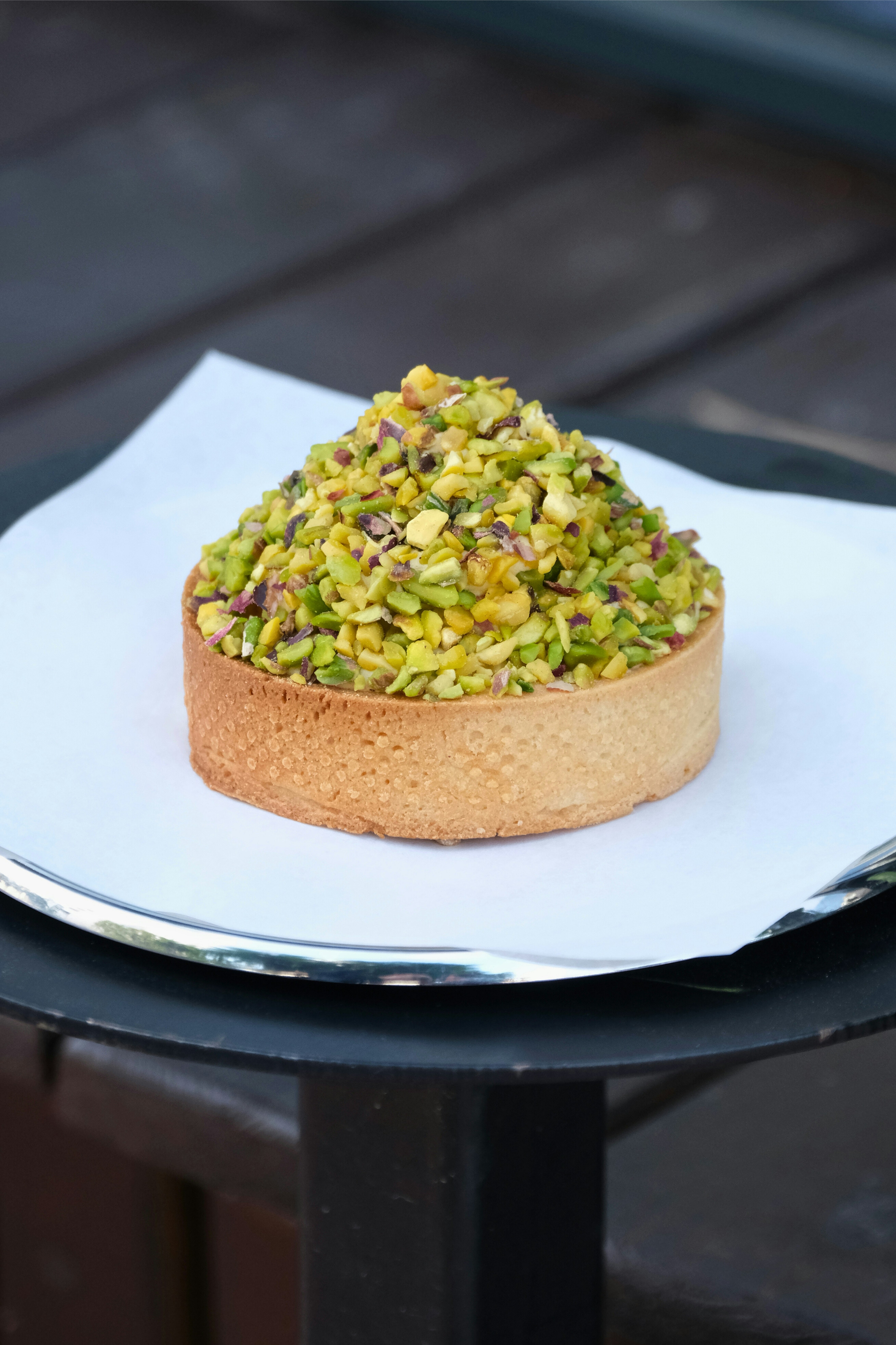 A delicious pistachio tart sits on a tray.