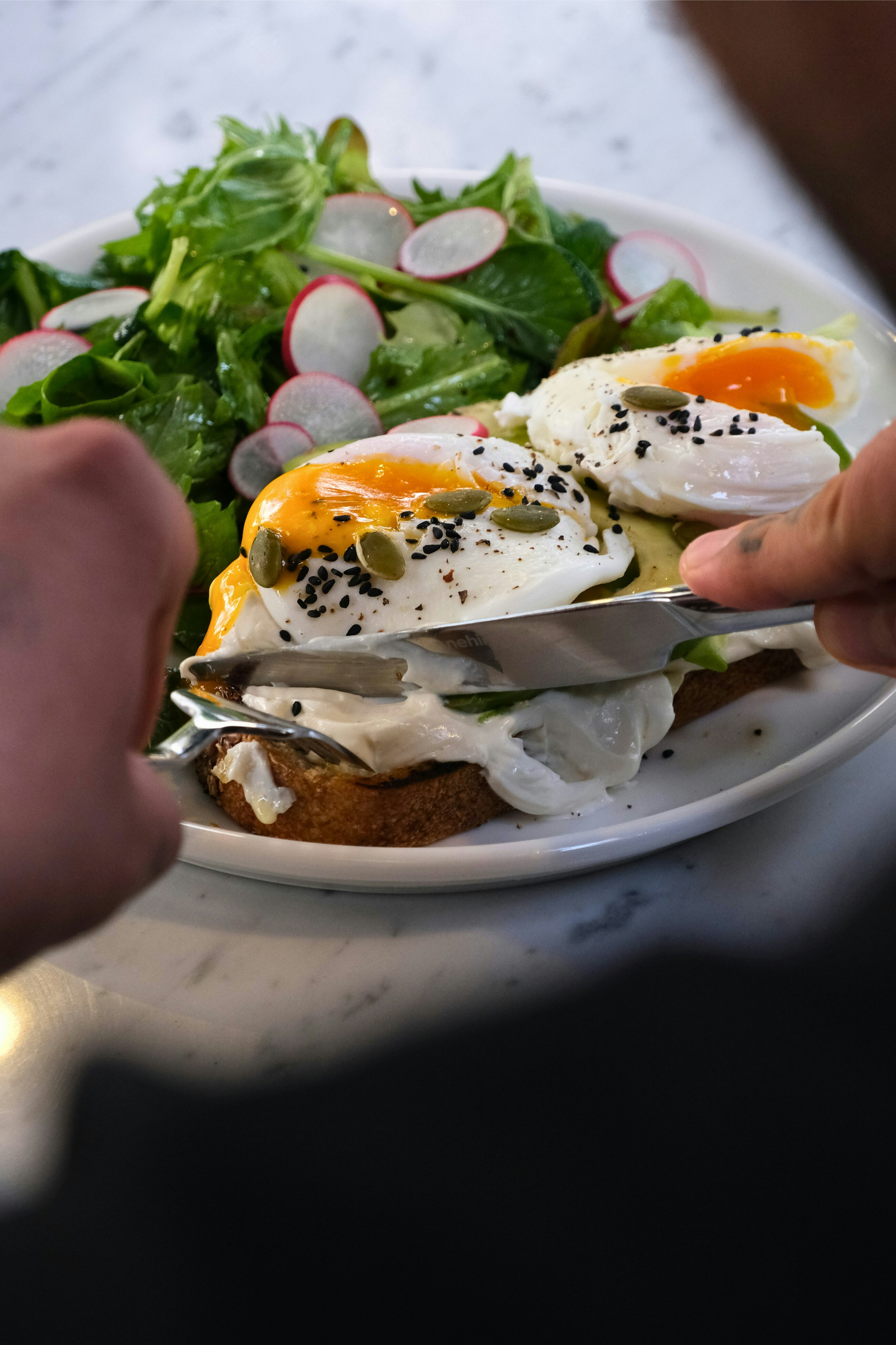 Someone is cutting into a delicious-looking poached egg dish.