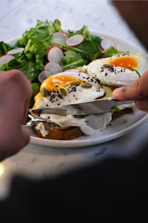 Someone is cutting into a delicious-looking poached egg dish.