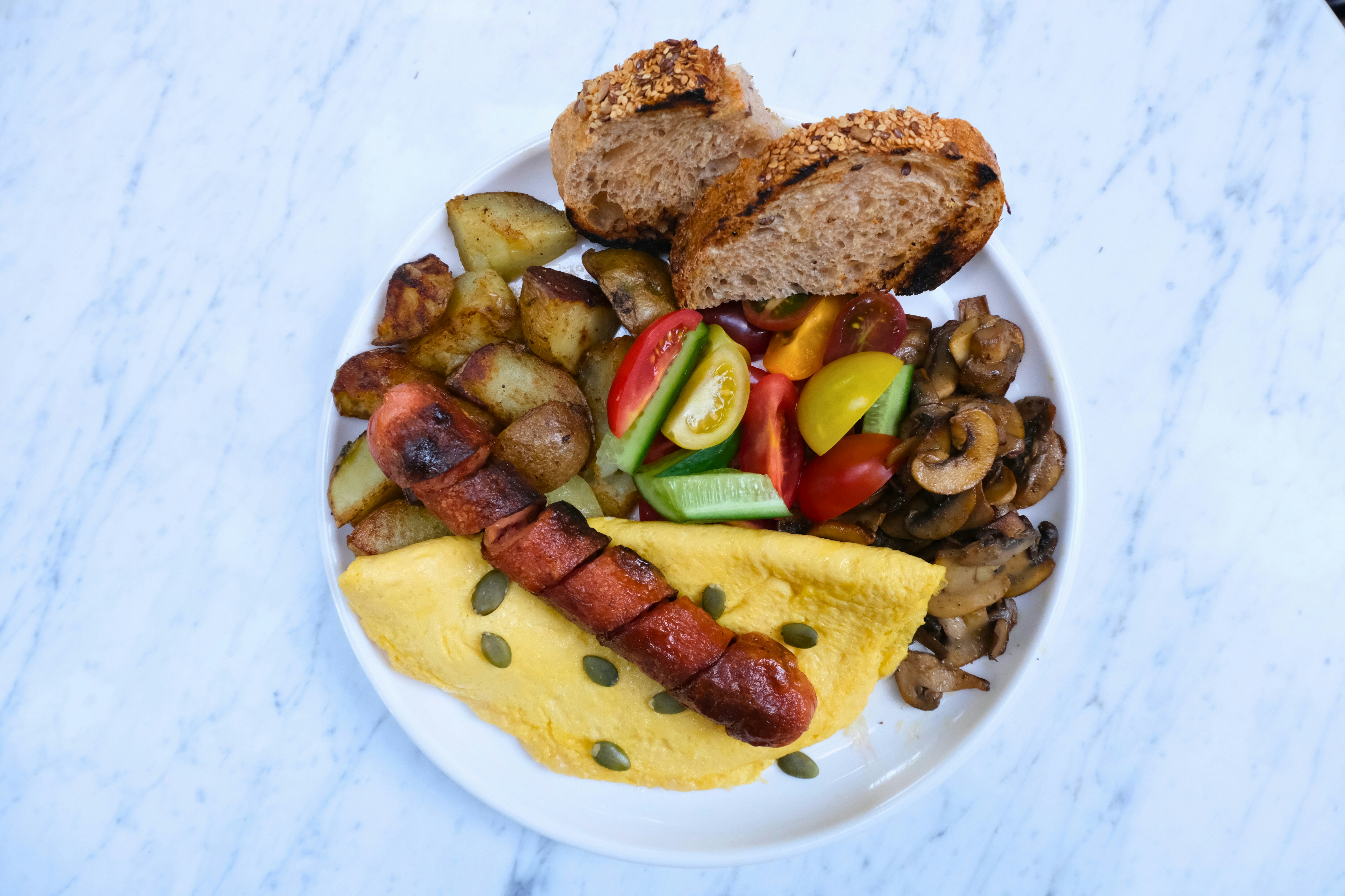 A plate of food, including sausage, vegetables, and bread.