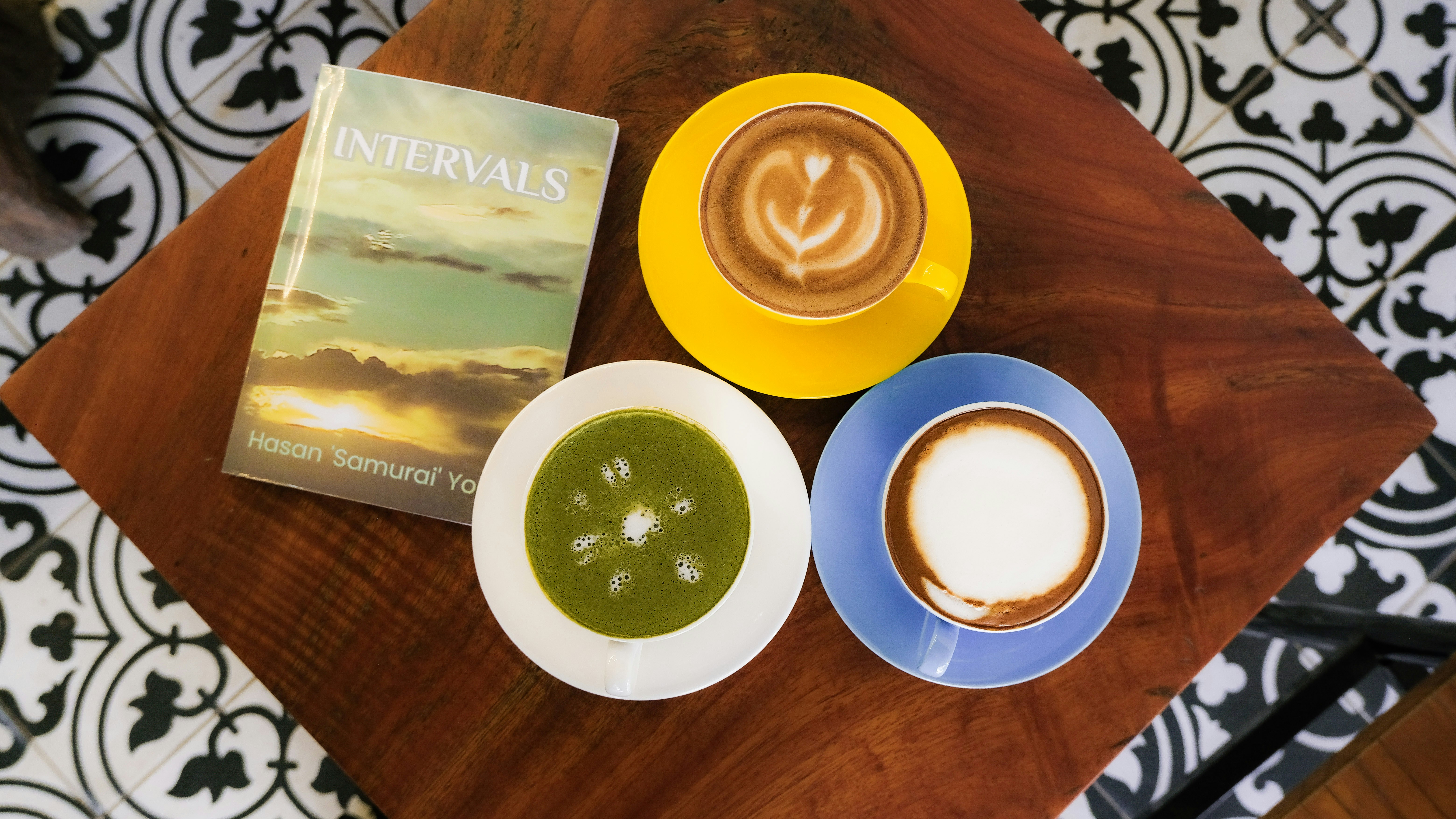Coffee and a book sit on a table.