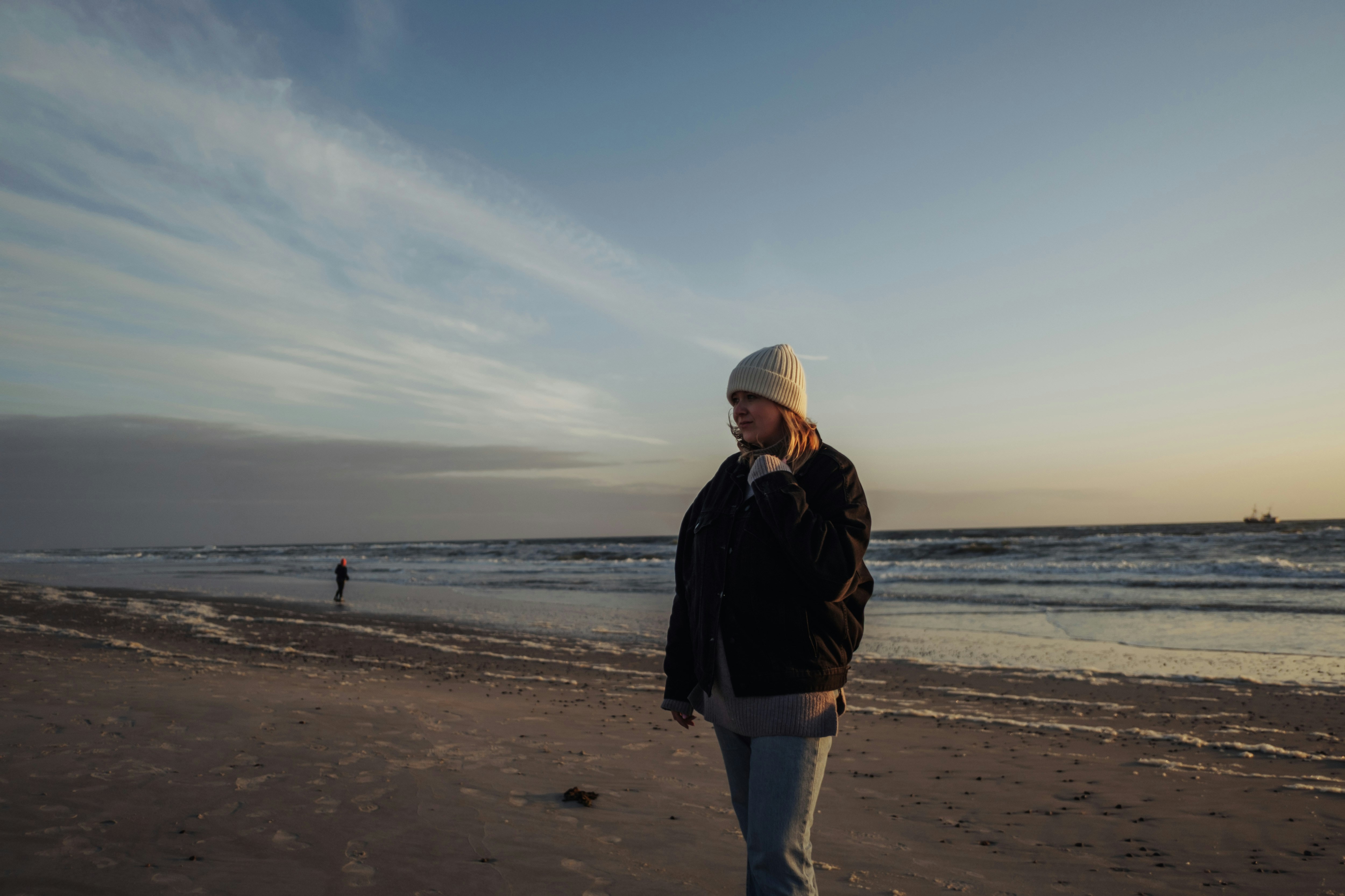 Woman walks on the beach at sunset.
