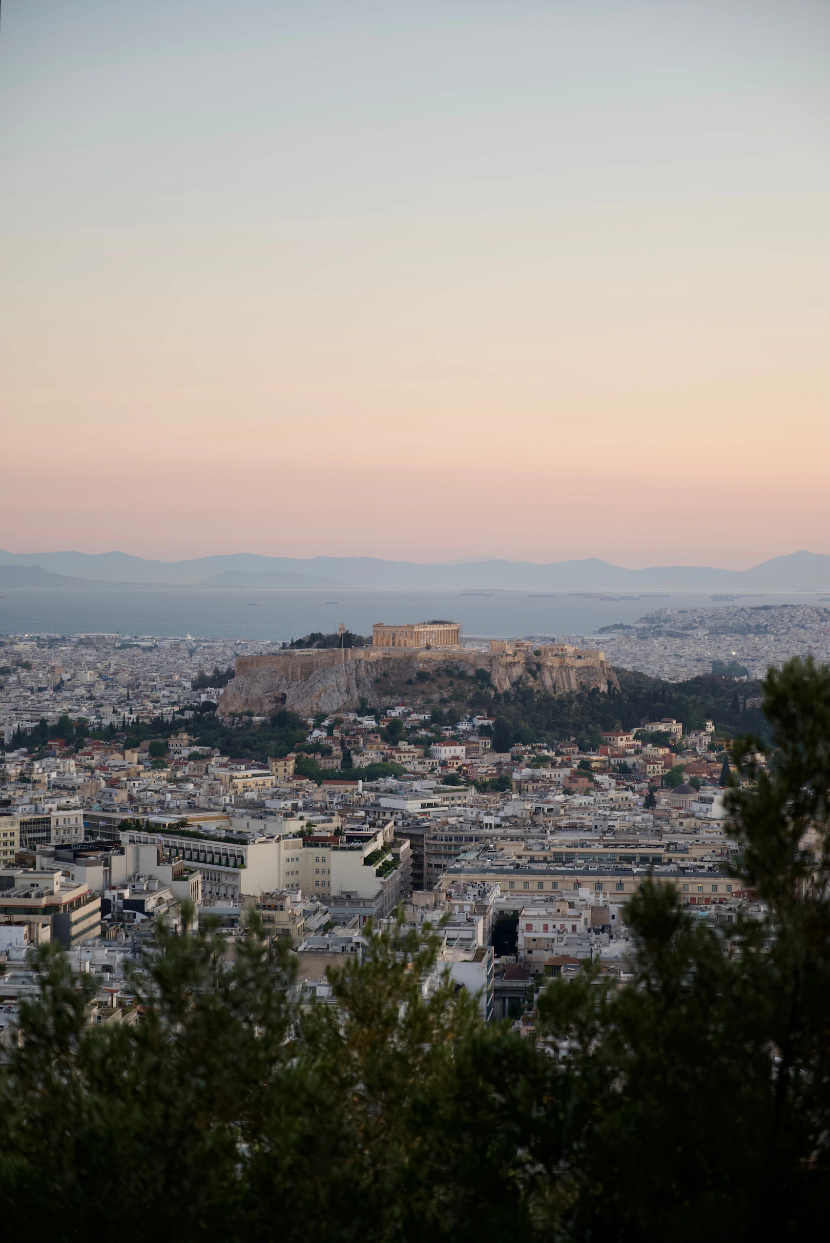 The Acropolis rising above the dense neighbourhoods of Athens at sunset
