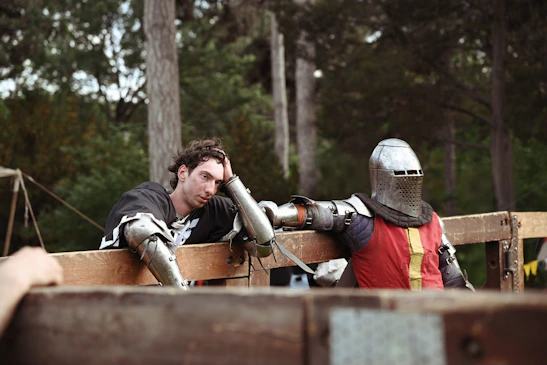 Two knights rest against the wooden barrier.