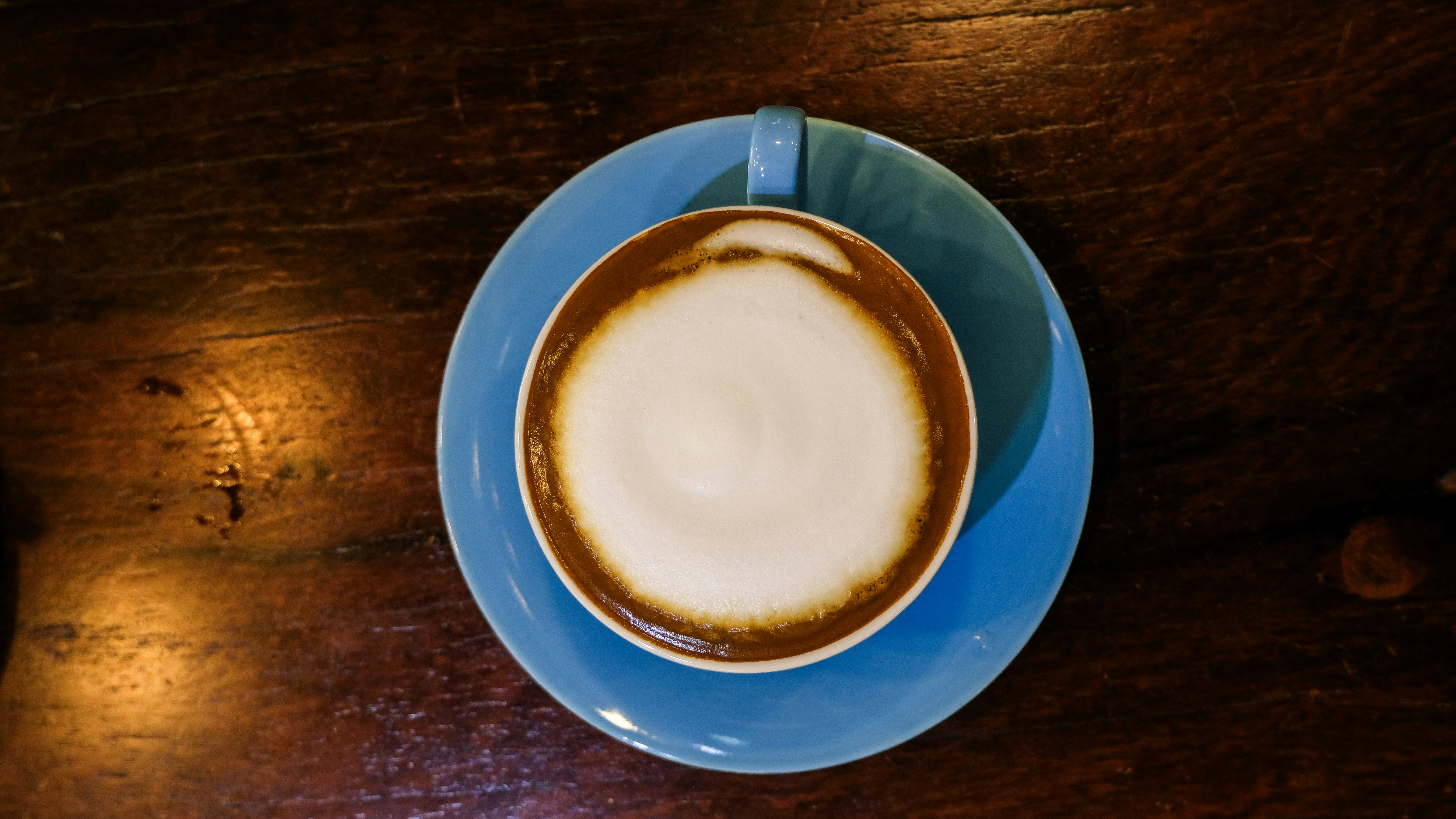 Cappuccino in a blue cup on a wooden table.