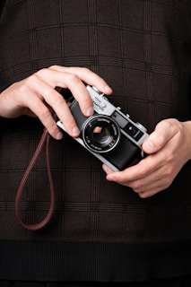 A person holds a classic olympus camera.