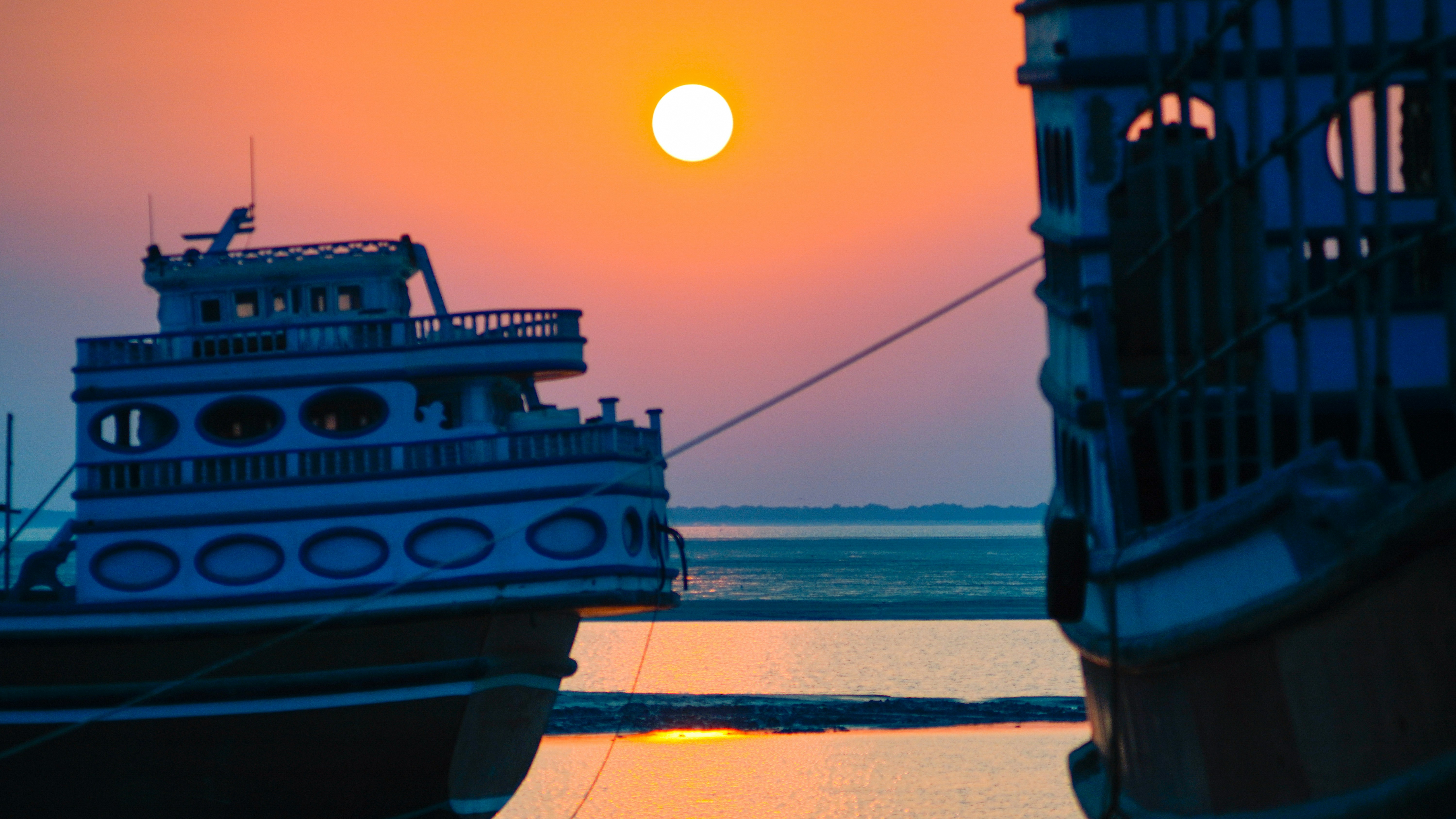 Boats are silhouetted against the setting sun.