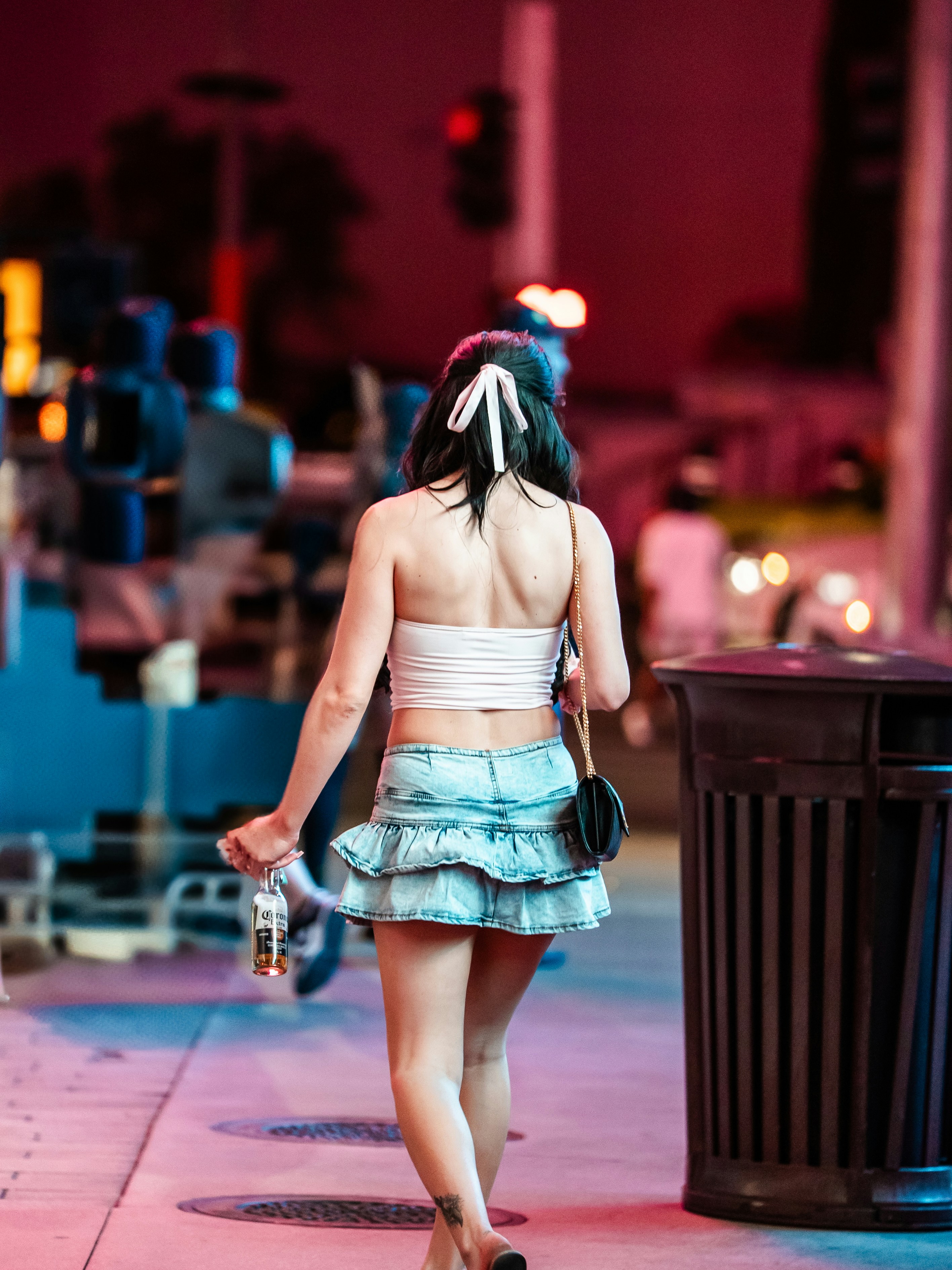 A woman walks down a city street at night.