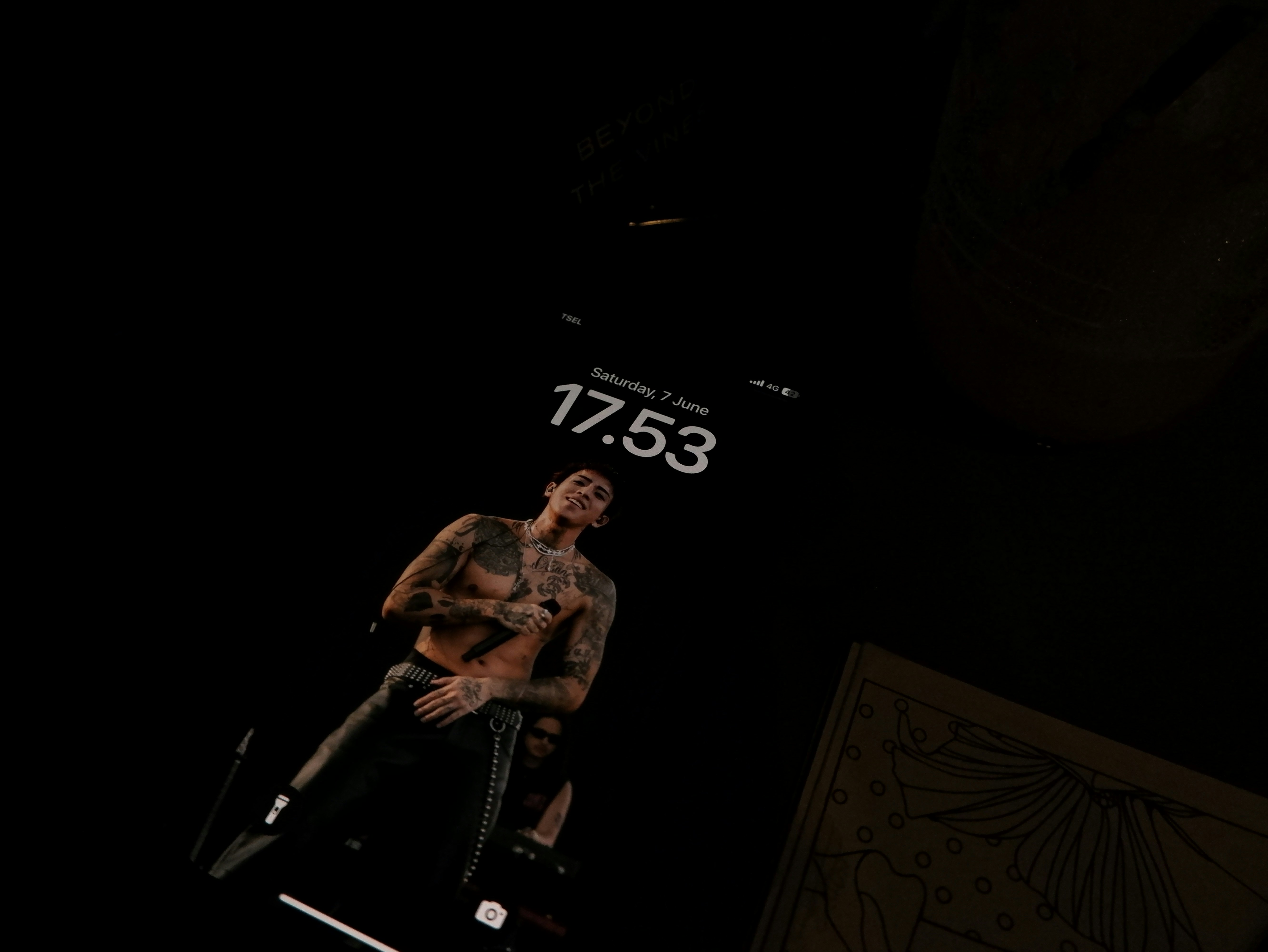 A phone shows a picture of a tattooed man.