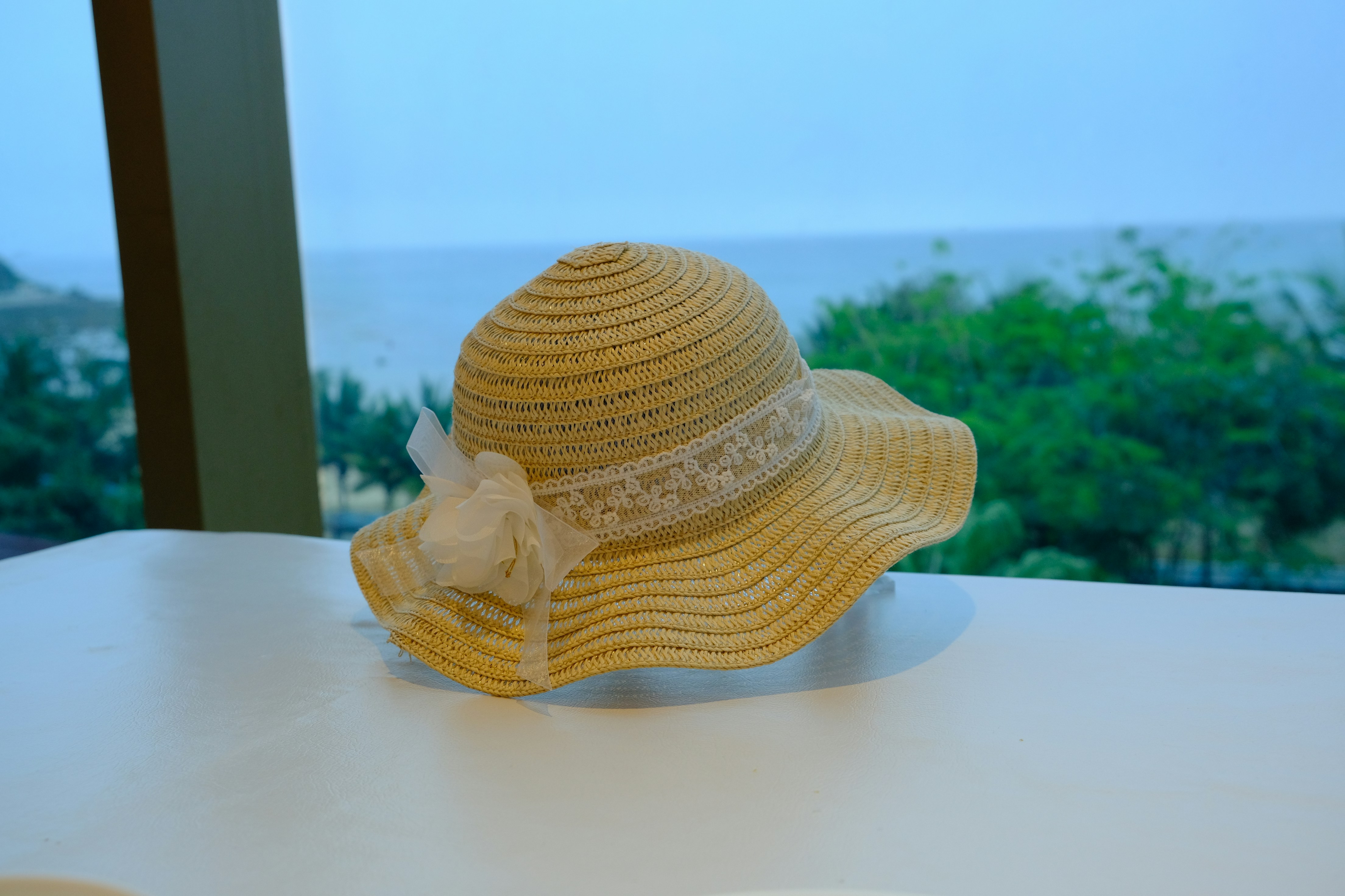 A woven sun hat sits by a window.